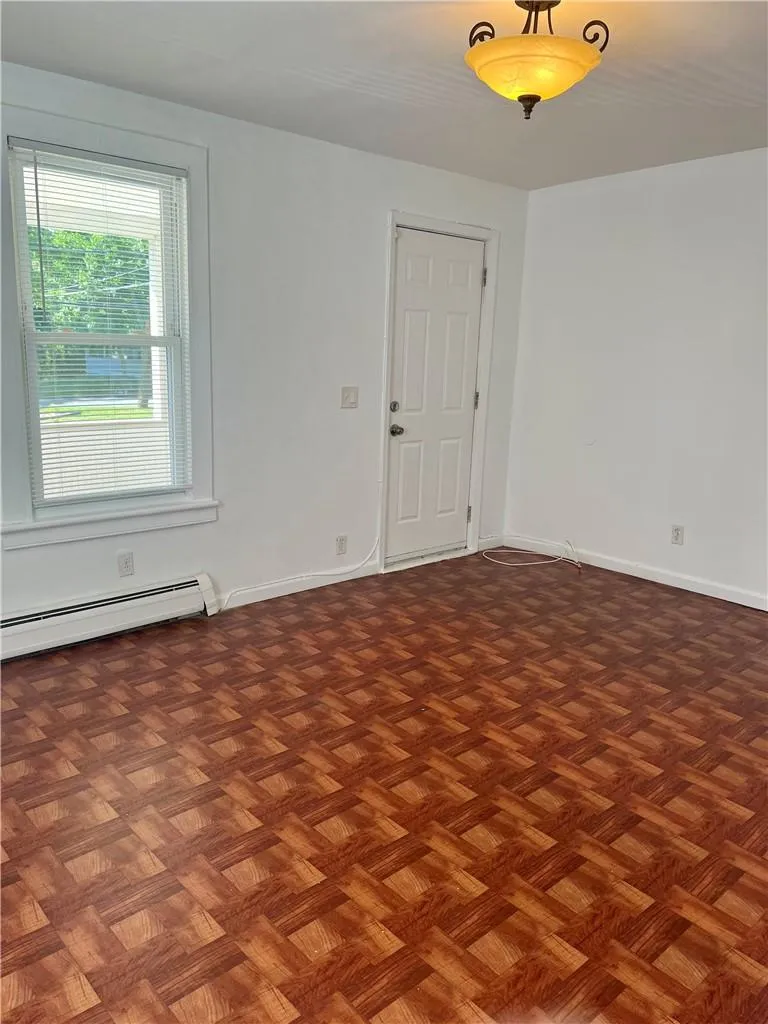 Livingroom featuring a baseboard heating unit and dark parquet floors Livingroom featuring a baseboard heating unit and dark parquet floors
