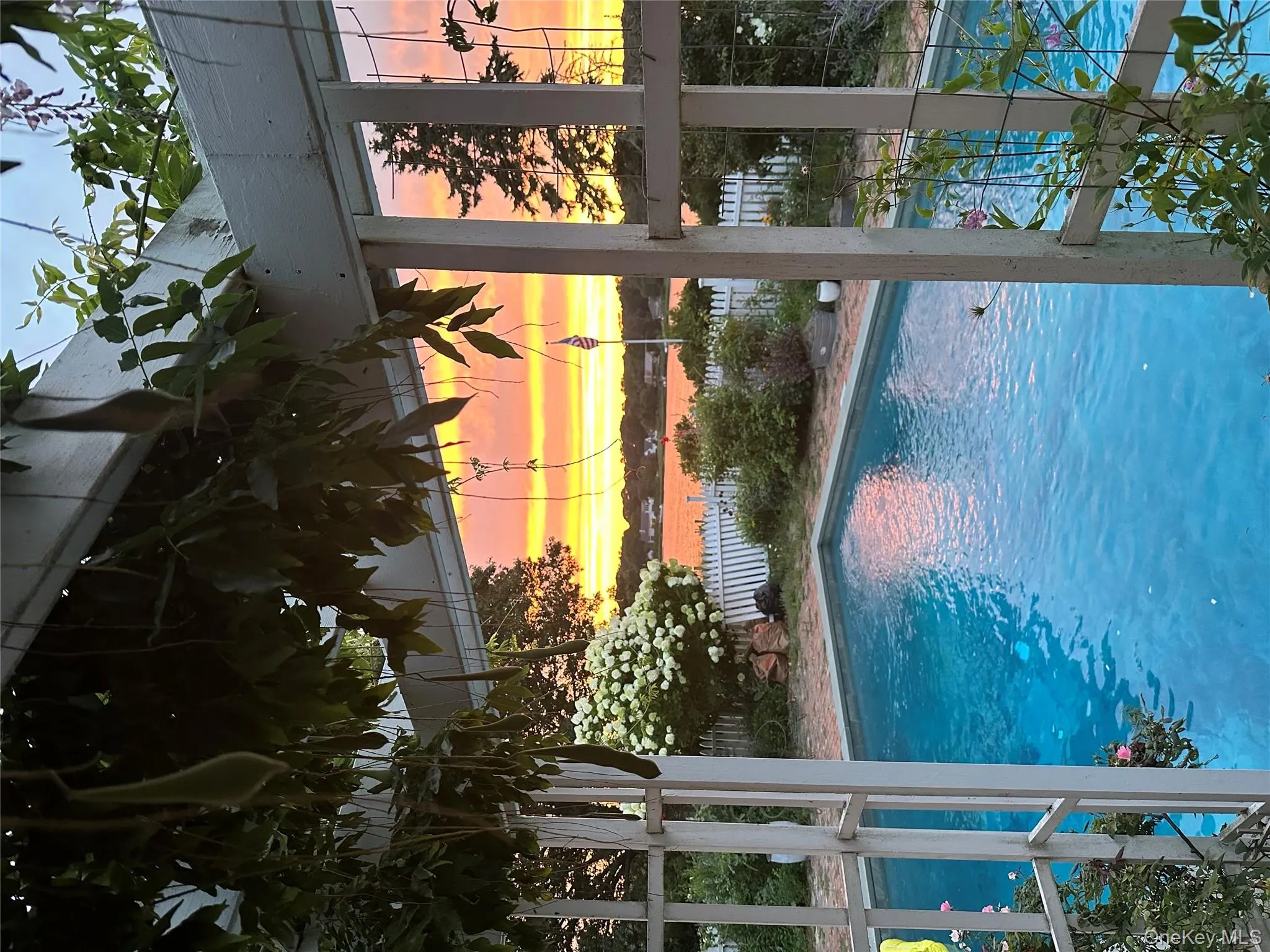 Pool at dusk featuring a fenced backyard and a water view Pool at dusk featuring a fenced backyard and a water view