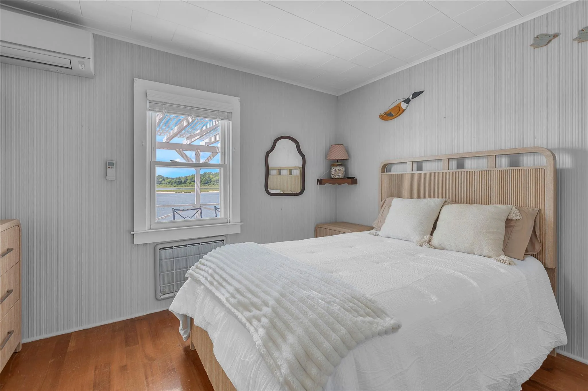 Bedroom featuring a wall mounted AC, crown molding, wood finished floors, and radiator Bedroom featuring a wall mounted AC, crown molding, wood finished floors, and radiator