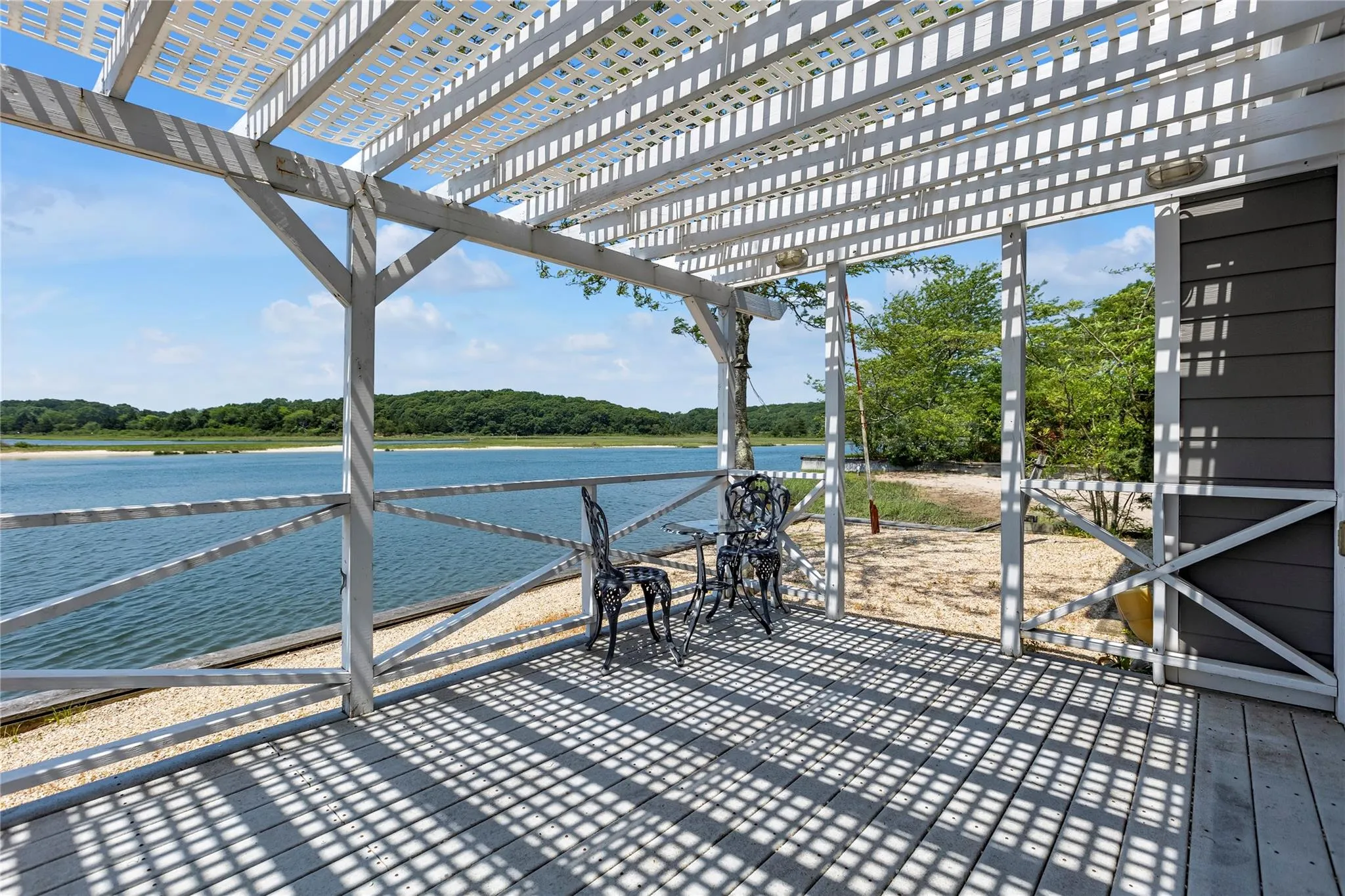 Deck featuring a water view, a pergola, and view of wooded area Deck featuring a water view, a pergola, and view of wooded area