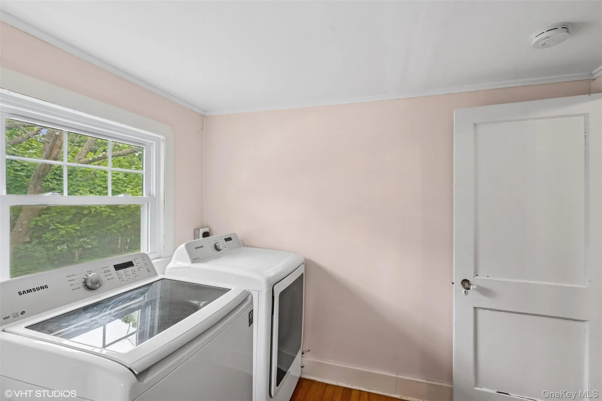 Laundry area with washing machine and dryer, crown molding, and wood finished floors Laundry area with washing machine and dryer, crown molding, and wood finished floors