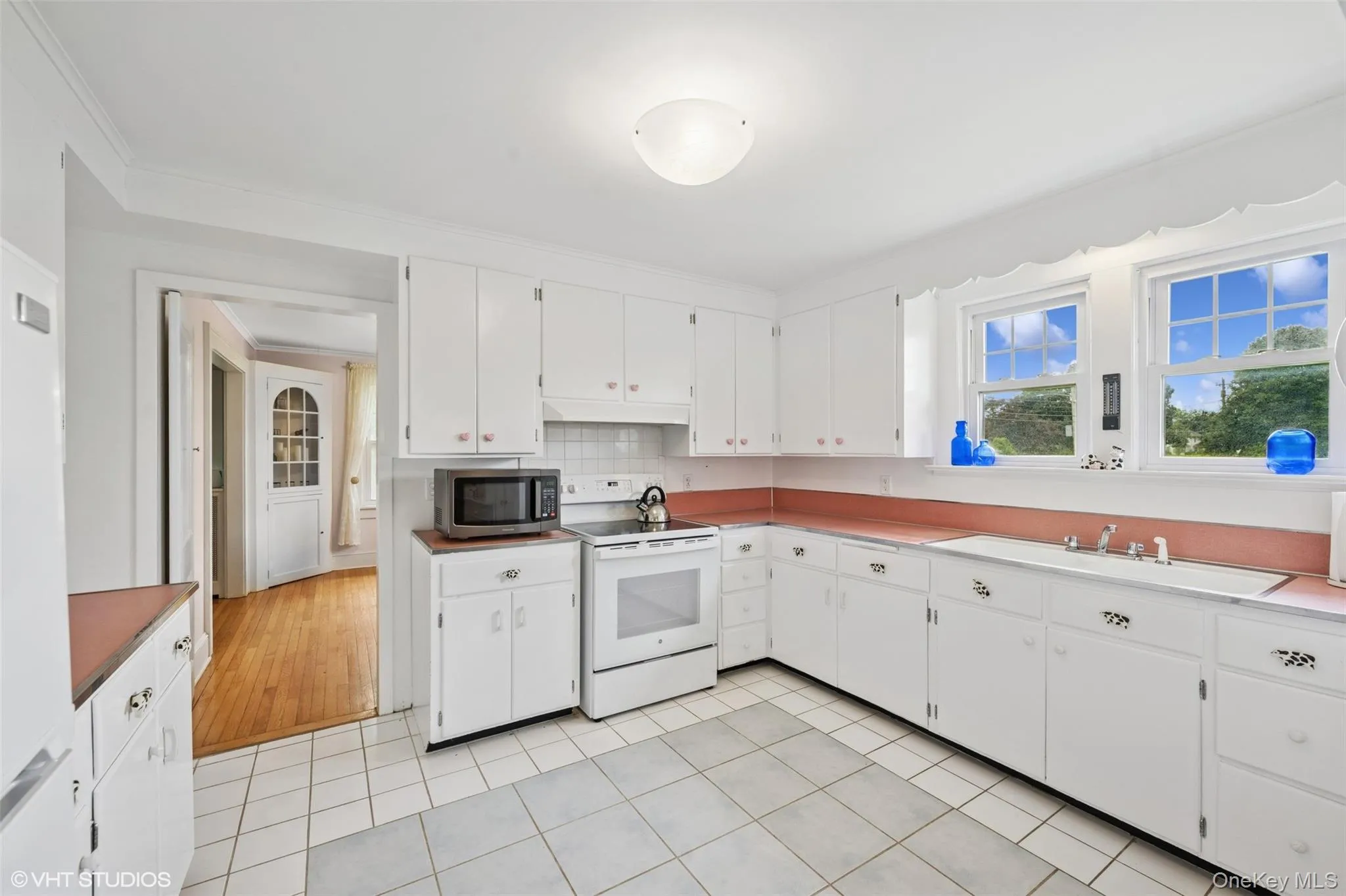 Kitchen with white electric range oven, stainless steel microwave, under cabinet range hood, white cabinets, and crown molding Kitchen with white electric range oven, stainless steel microwave, under cabinet range hood, white cabinets, and crown molding