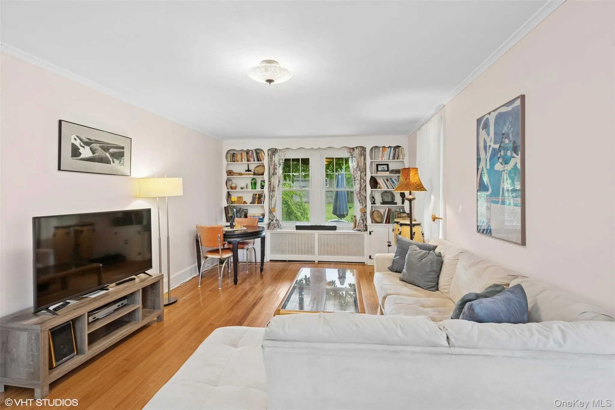 Living area with crown molding, wood finished floors, and radiator heating unit Living area with crown molding, wood finished floors, and radiator heating unit