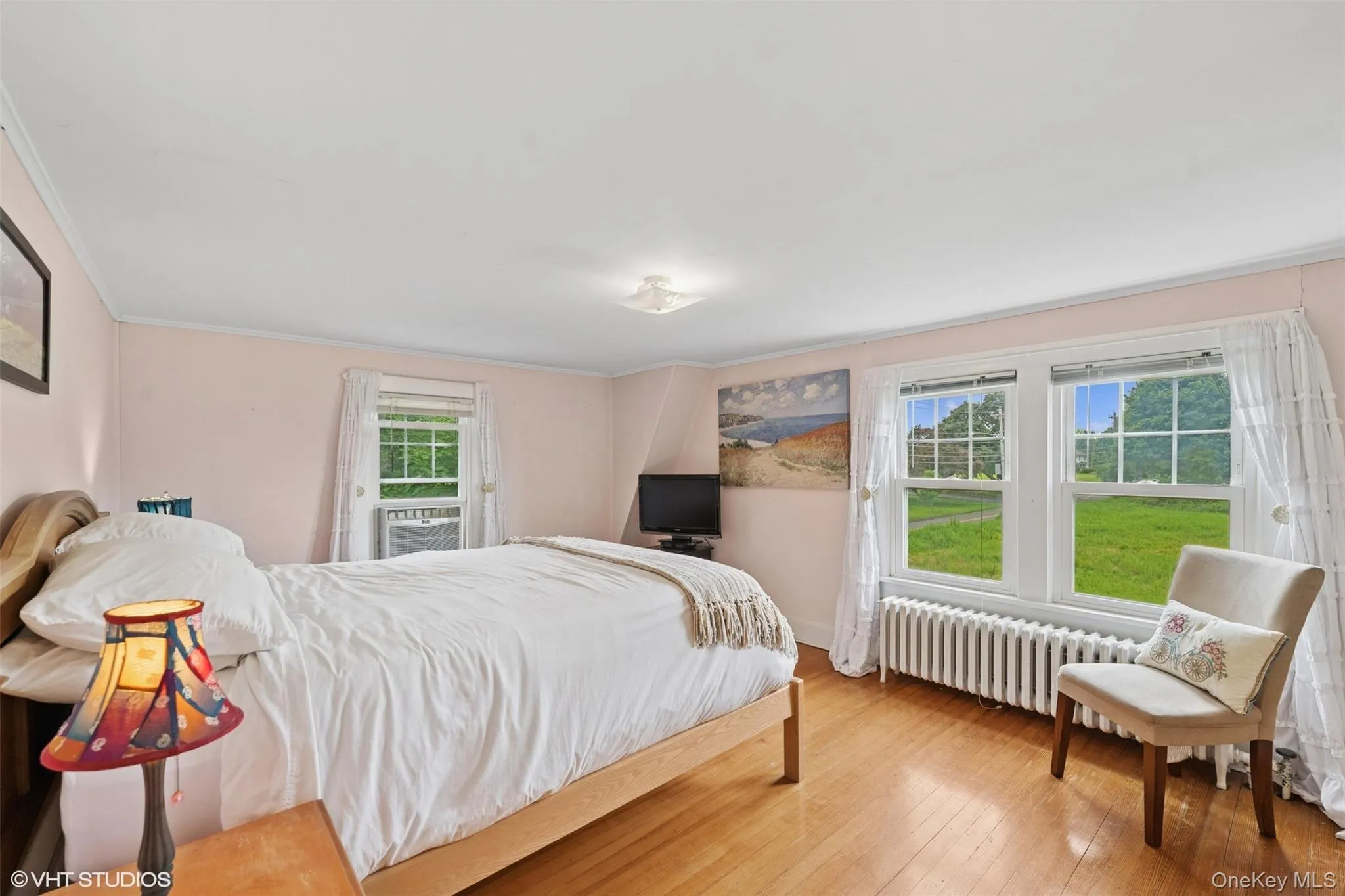 Bedroom with radiator heating unit, ornamental molding, and wood-type flooring Bedroom with radiator heating unit, ornamental molding, and wood-type flooring