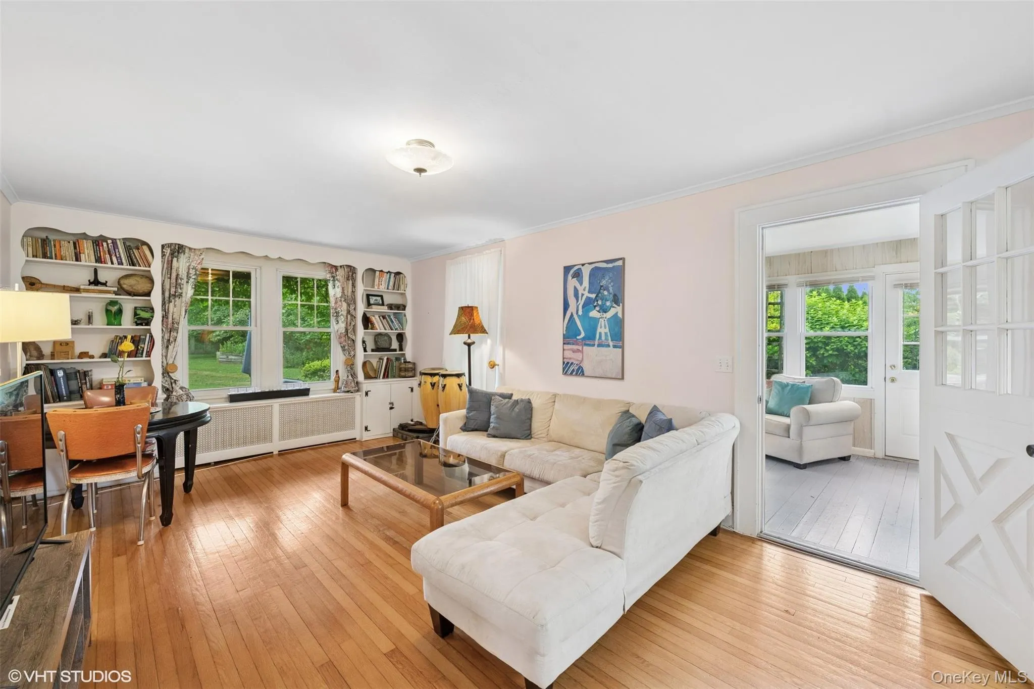 Living area featuring wood-type flooring, plenty of natural light, radiator, and crown molding Living area featuring wood-type flooring, plenty of natural light, radiator, and crown molding