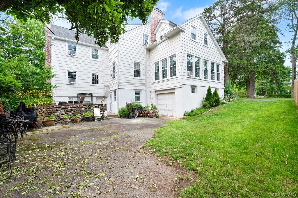 Rear view of property featuring driveway, a garage, and yard. Rear view of property featuring driveway, a garage, and yard.
