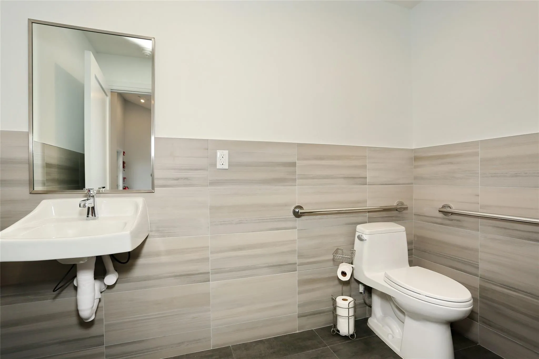 Half bathroom featuring tile walls, tile patterned flooring, and wainscoting Half bathroom featuring tile walls, tile patterned flooring, and wainscoting