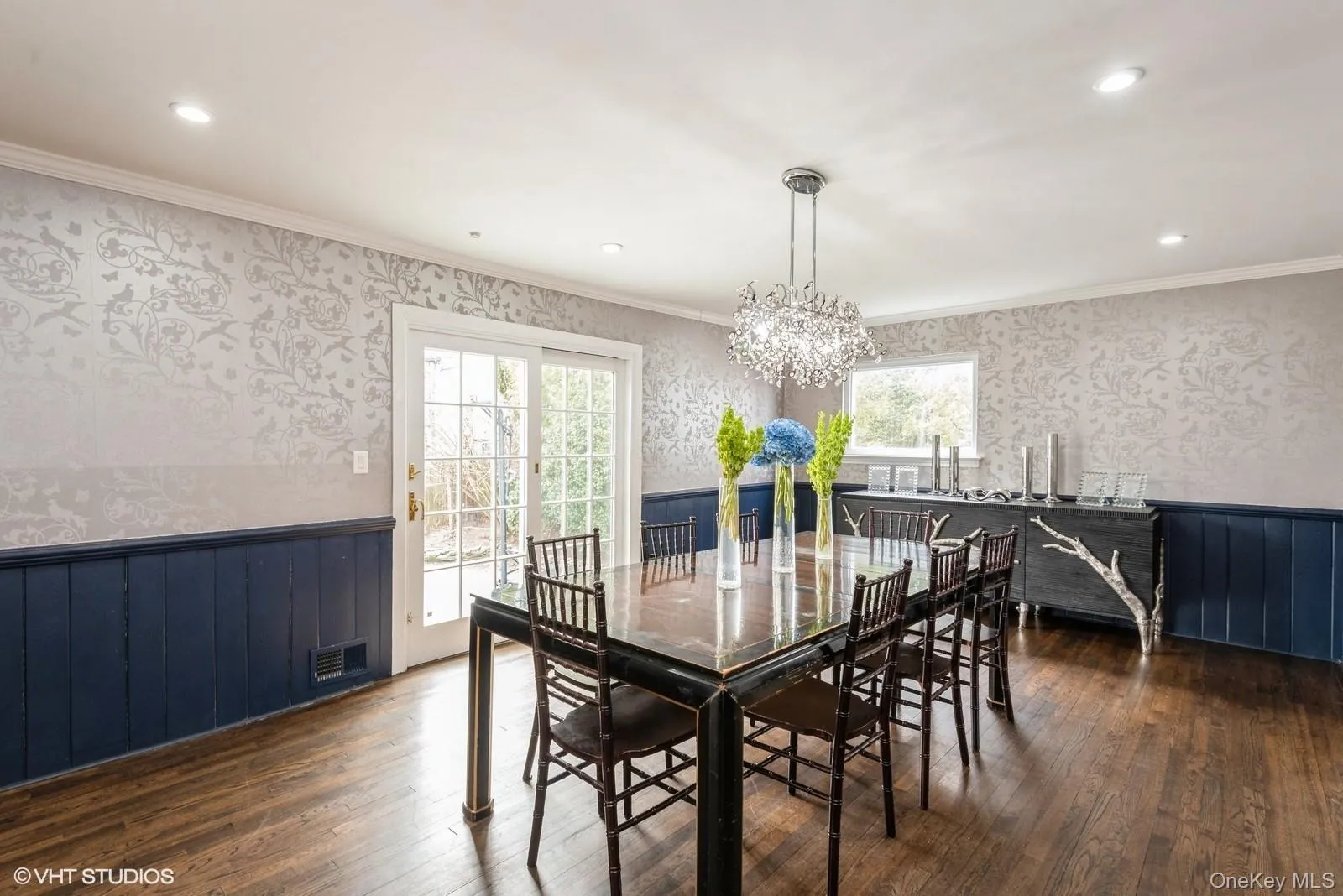 Dining area with wallpapered walls, wainscoting, ornamental molding, dark wood-style floors, and healthy amount of natural light Dining area with wallpapered walls, wainscoting, ornamental molding, dark wood-style floors, and healthy amount of natural light