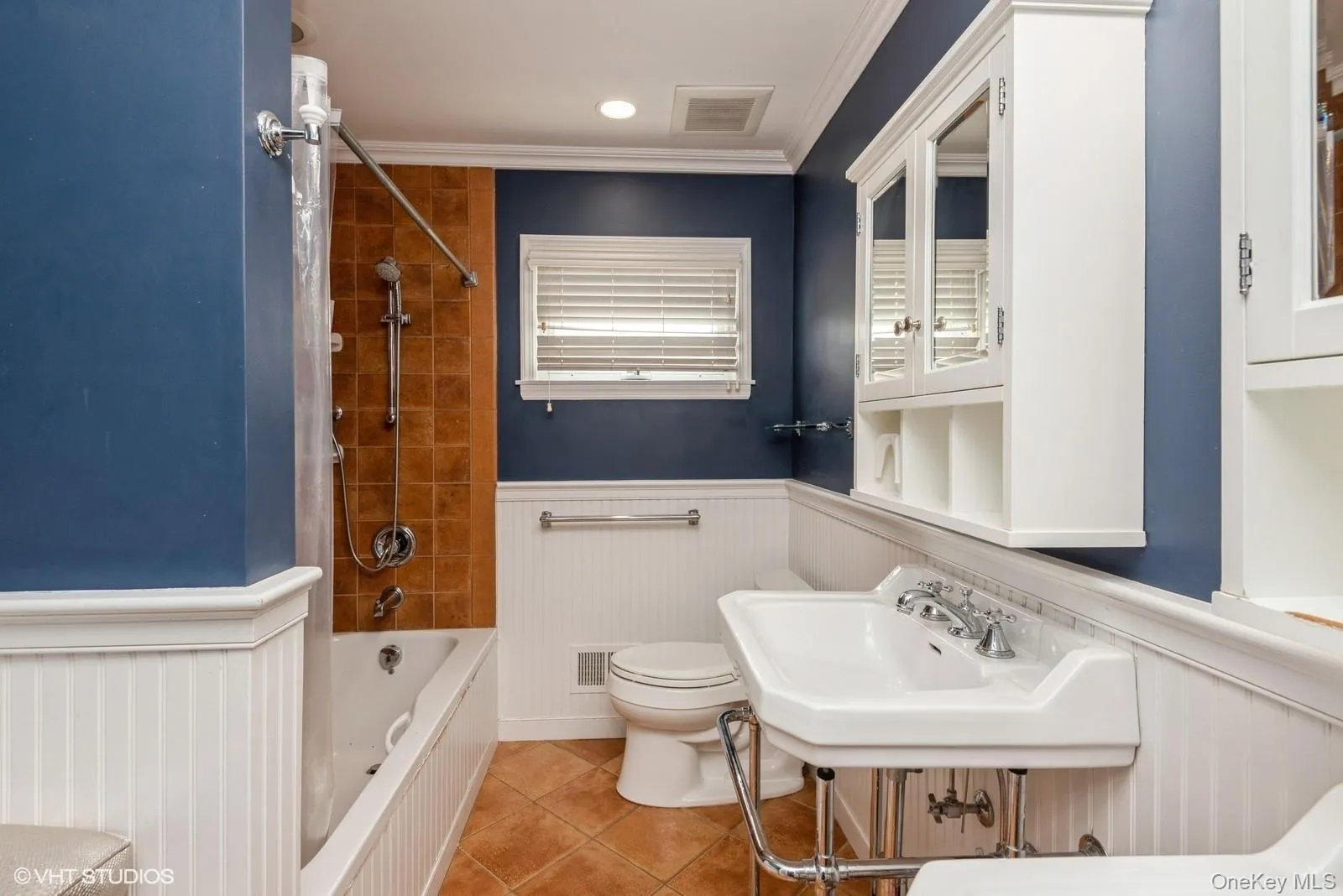 Bathroom featuring a wainscoted wall, washtub / shower combination, light tile patterned floors, crown molding, and recessed lighting Bathroom featuring a wainscoted wall, washtub / shower combination, light tile patterned floors, crown molding, and recessed lighting