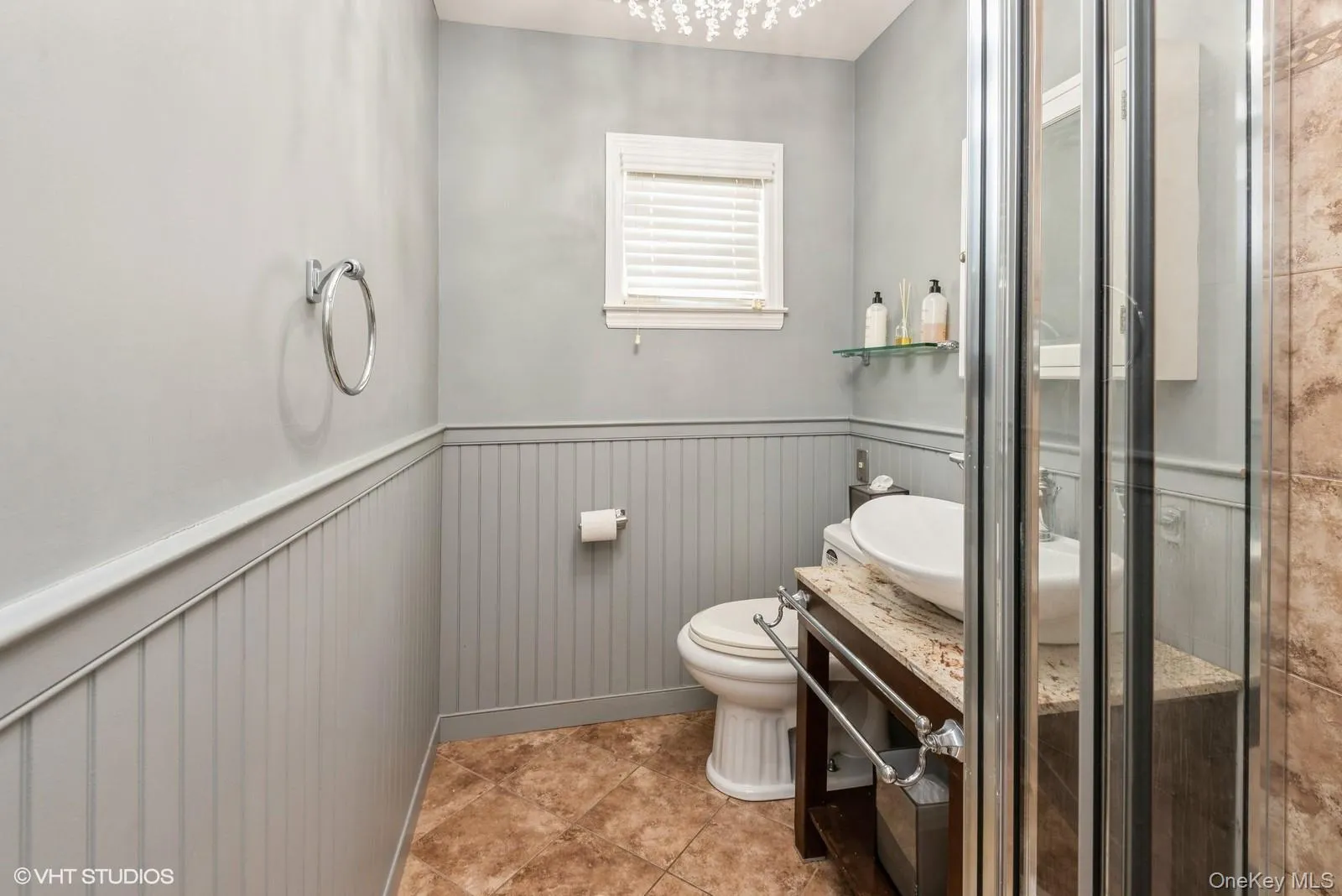 Bathroom with wainscoting, vanity, light tile patterned floors, and a stall shower Bathroom with wainscoting, vanity, light tile patterned floors, and a stall shower