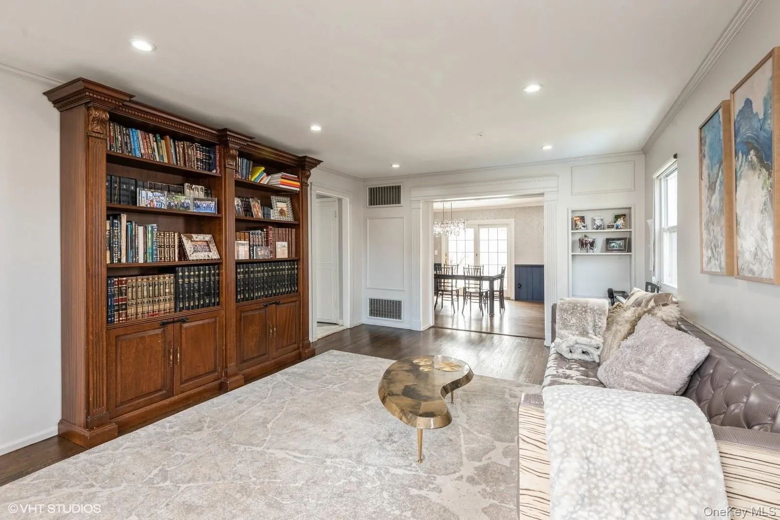 Living area featuring crown molding, wood finished floors, a chandelier, recessed lighting, and a decorative wall Living area featuring crown molding, wood finished floors, a chandelier, recessed lighting, and a decorative wall