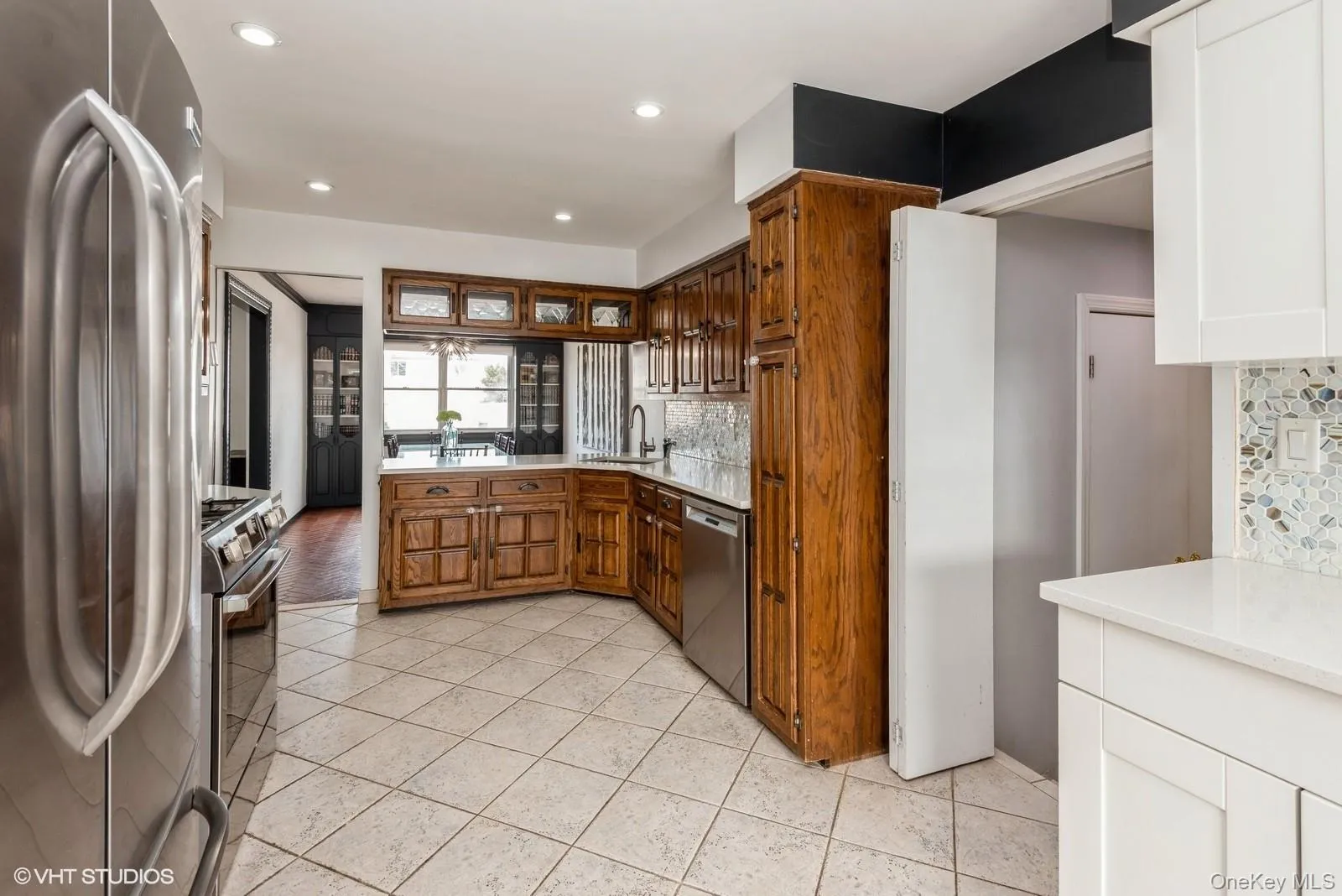 Kitchen featuring appliances with stainless steel finishes, backsplash, recessed lighting, light tile patterned flooring, and a peninsula Kitchen featuring appliances with stainless steel finishes, backsplash, recessed lighting, light tile patterned flooring, and a peninsula
