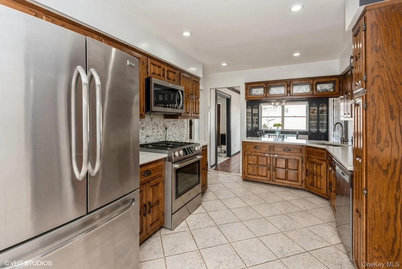 Kitchen with stainless steel appliances, light countertops, recessed lighting, decorative backsplash, and light tile patterned flooring Kitchen with stainless steel appliances, light countertops, recessed lighting, decorative backsplash, and light tile patterned flooring