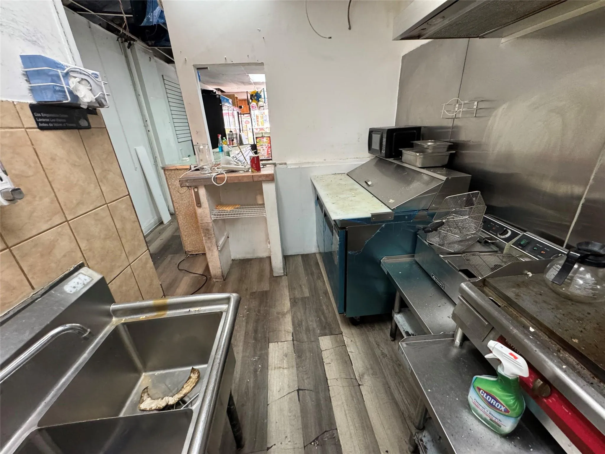 Kitchen with wood finished floors, black microwave, and extractor fan Kitchen with wood finished floors, black microwave, and extractor fan