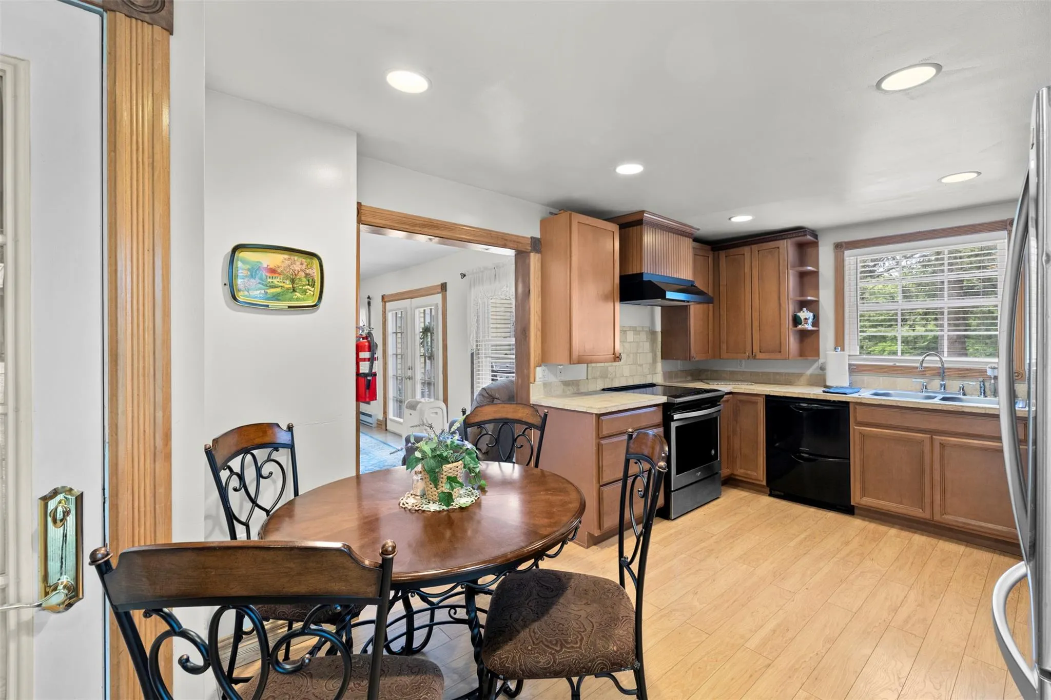 Kitchen featuring dishwasher, stainless steel range with electric stovetop, light wood-style floors, light countertops, and backsplash Kitchen featuring dishwasher, stainless steel range with electric stovetop, light wood-style floors, light countertops, and backsplash