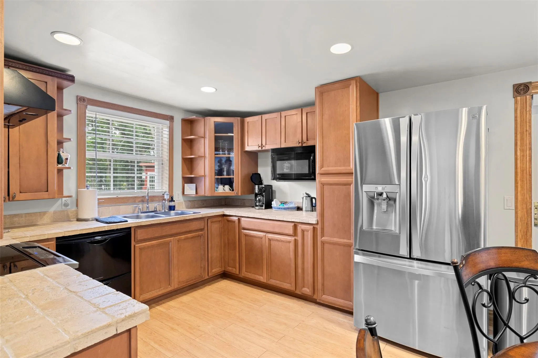 Kitchen featuring black appliances, open shelves, ventilation hood, recessed lighting, and glass insert cabinets Kitchen featuring black appliances, open shelves, ventilation hood, recessed lighting, and glass insert cabinets