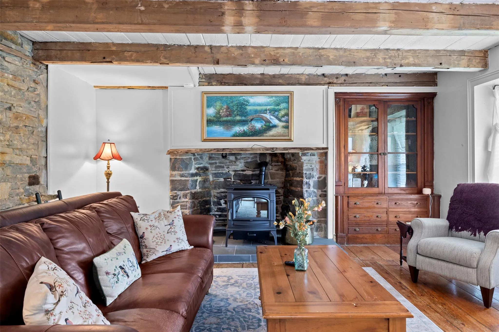 Living area featuring a wood stove, hardwood / wood-style floors, and a wooden ceiling with exposed beams Living area featuring a wood stove, hardwood / wood-style floors, and a wooden ceiling with exposed beams