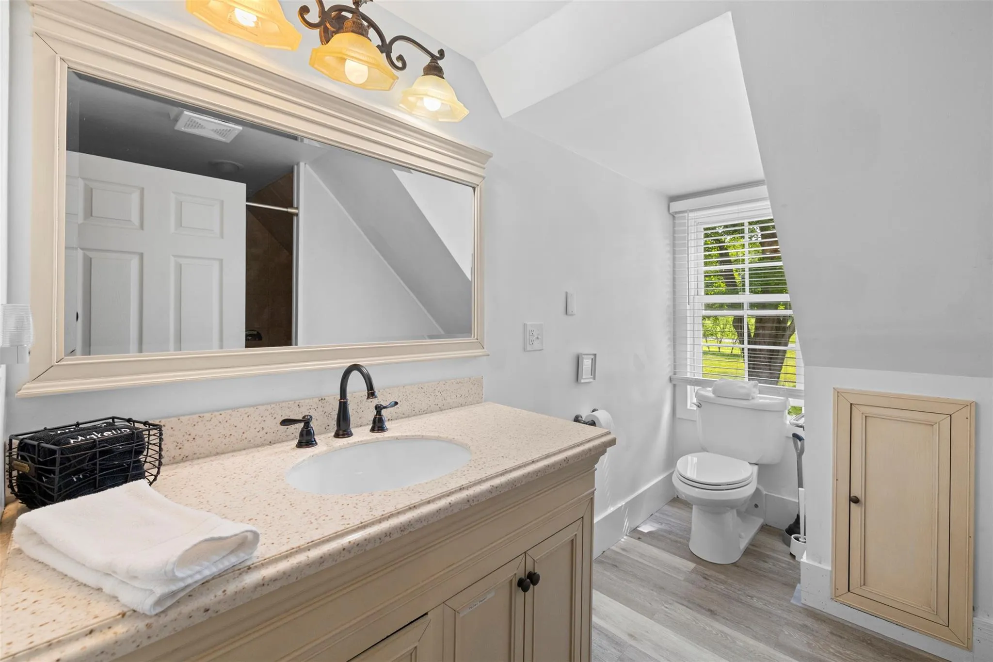 Bathroom featuring vaulted ceiling, vanity, wood finished floors, and a shower Bathroom featuring vaulted ceiling, vanity, wood finished floors, and a shower
