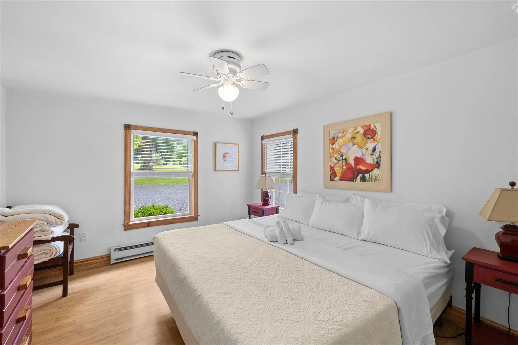 Bedroom featuring a baseboard heating unit, light wood-style flooring, and a ceiling fan Bedroom featuring a baseboard heating unit, light wood-style flooring, and a ceiling fan