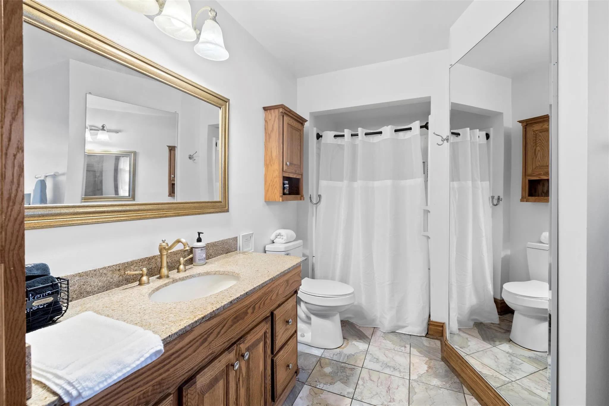 Full bath featuring vanity, marble finish flooring, and a shower with curtain Full bath featuring vanity, marble finish flooring, and a shower with curtain