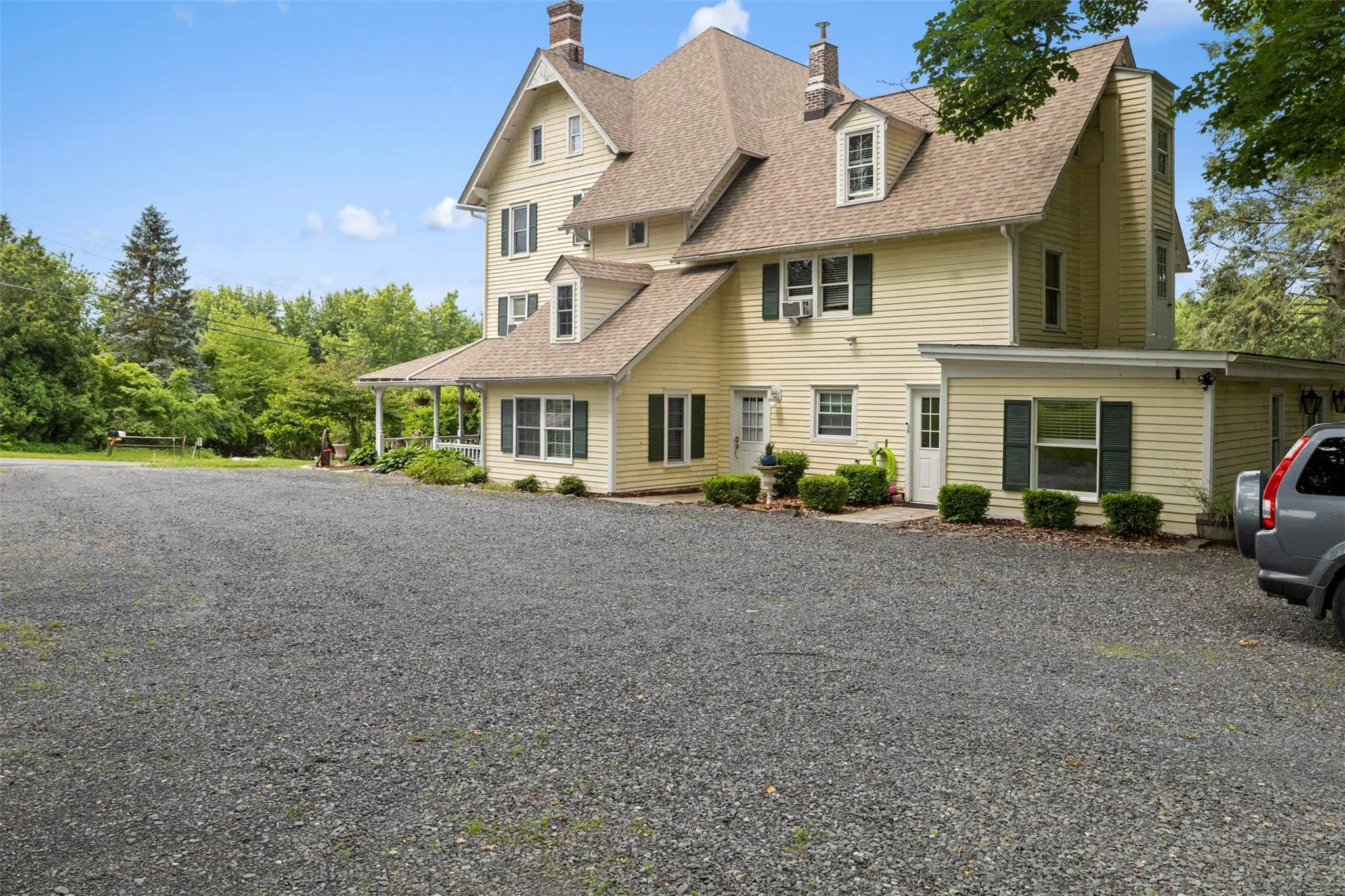 View of front of home with a shingled roof, a chimney, and gravel driveway View of front of home with a shingled roof, a chimney, and gravel driveway