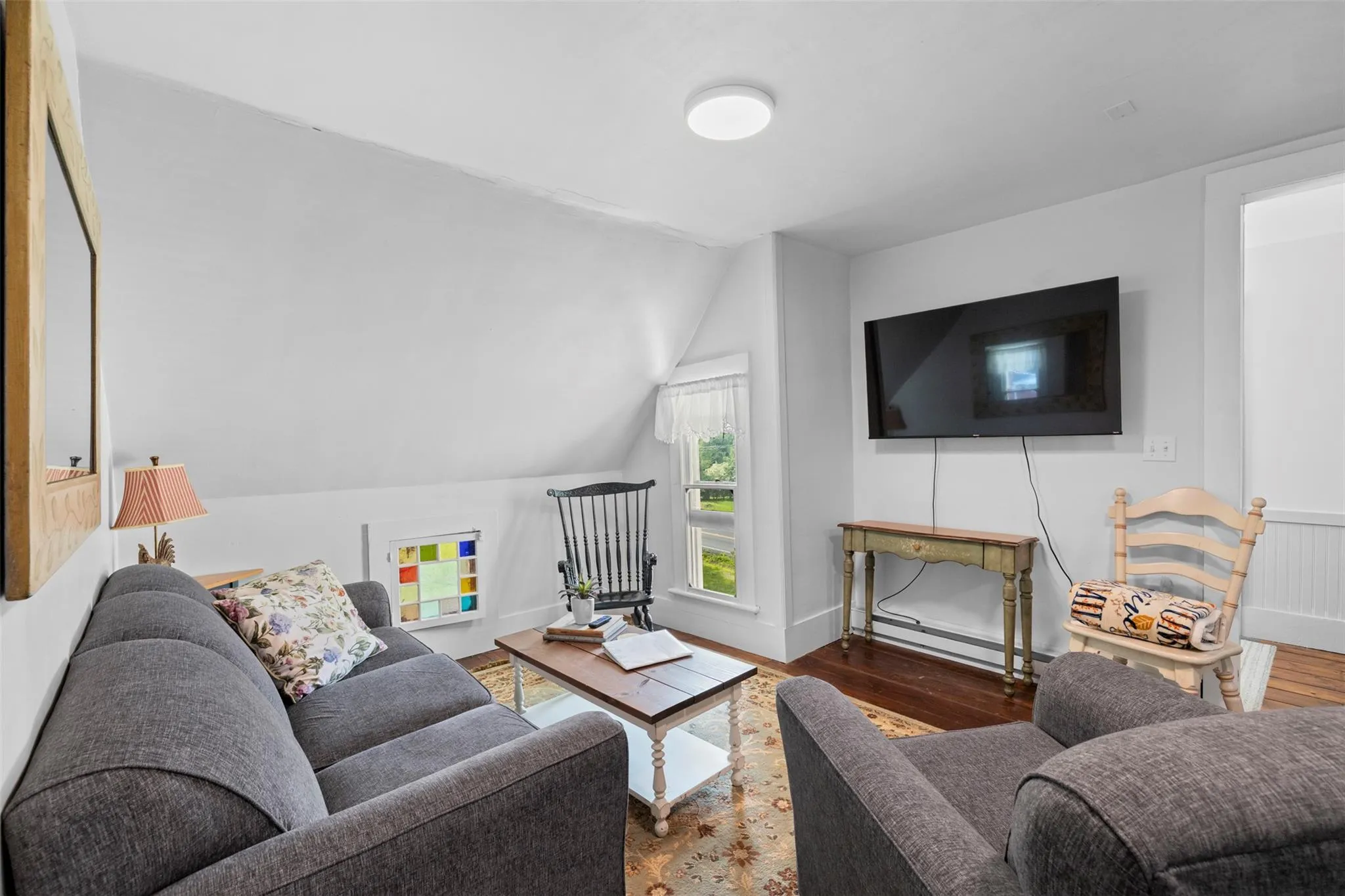 Living area featuring a baseboard radiator, wood finished floors, and vaulted ceiling Living area featuring a baseboard radiator, wood finished floors, and vaulted ceiling