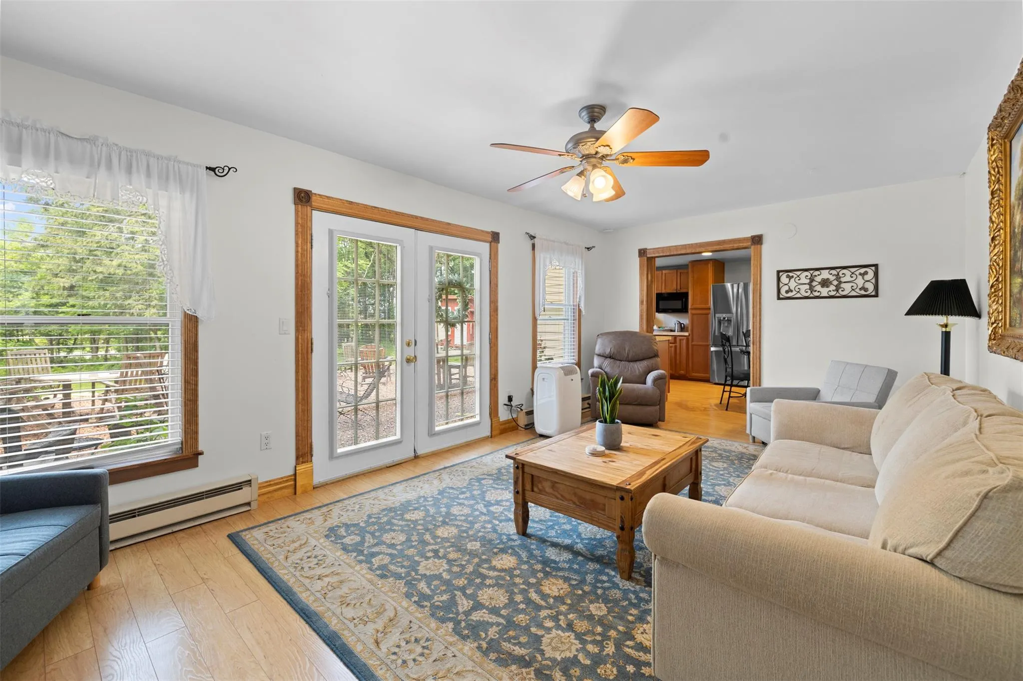 Living area featuring a baseboard radiator, healthy amount of natural light, ceiling fan, and light wood-style floors Living area featuring a baseboard radiator, healthy amount of natural light, ceiling fan, and light wood-style floors