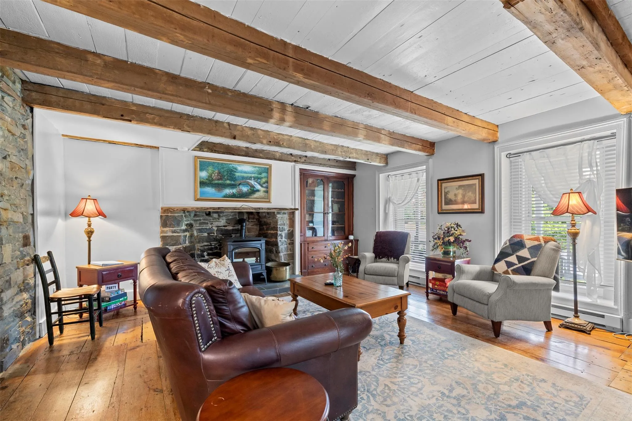 Living area with a wood stove, wood-type flooring, and a wood ceiling with exposed beams Living area with a wood stove, wood-type flooring, and a wood ceiling with exposed beams
