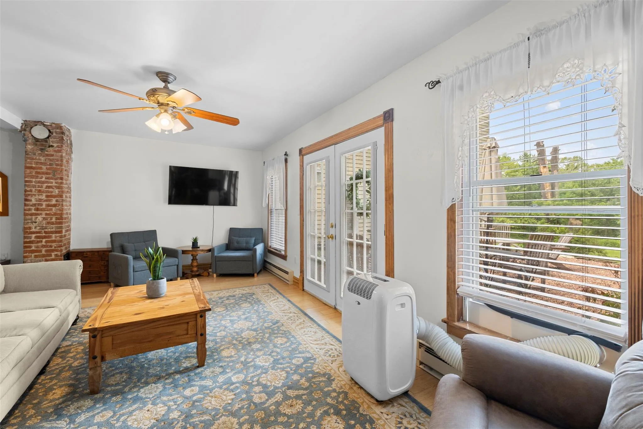 Living room featuring a ceiling fan, light wood-type flooring, and a baseboard heating unit Living room featuring a ceiling fan, light wood-type flooring, and a baseboard heating unit