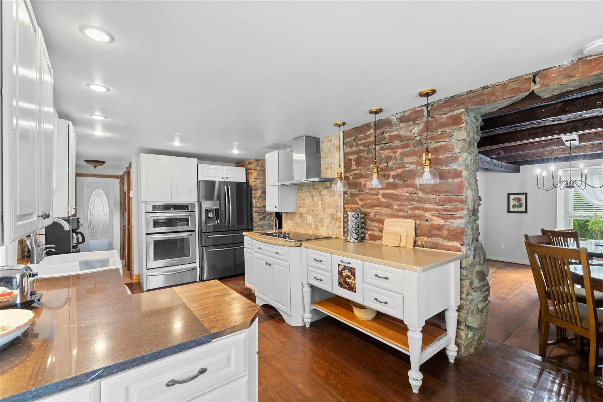 Kitchen with wall chimney exhaust hood, stainless steel appliances, a warming drawer, decorative backsplash, and white cabinetry Kitchen with wall chimney exhaust hood, stainless steel appliances, a warming drawer, decorative backsplash, and white cabinetry