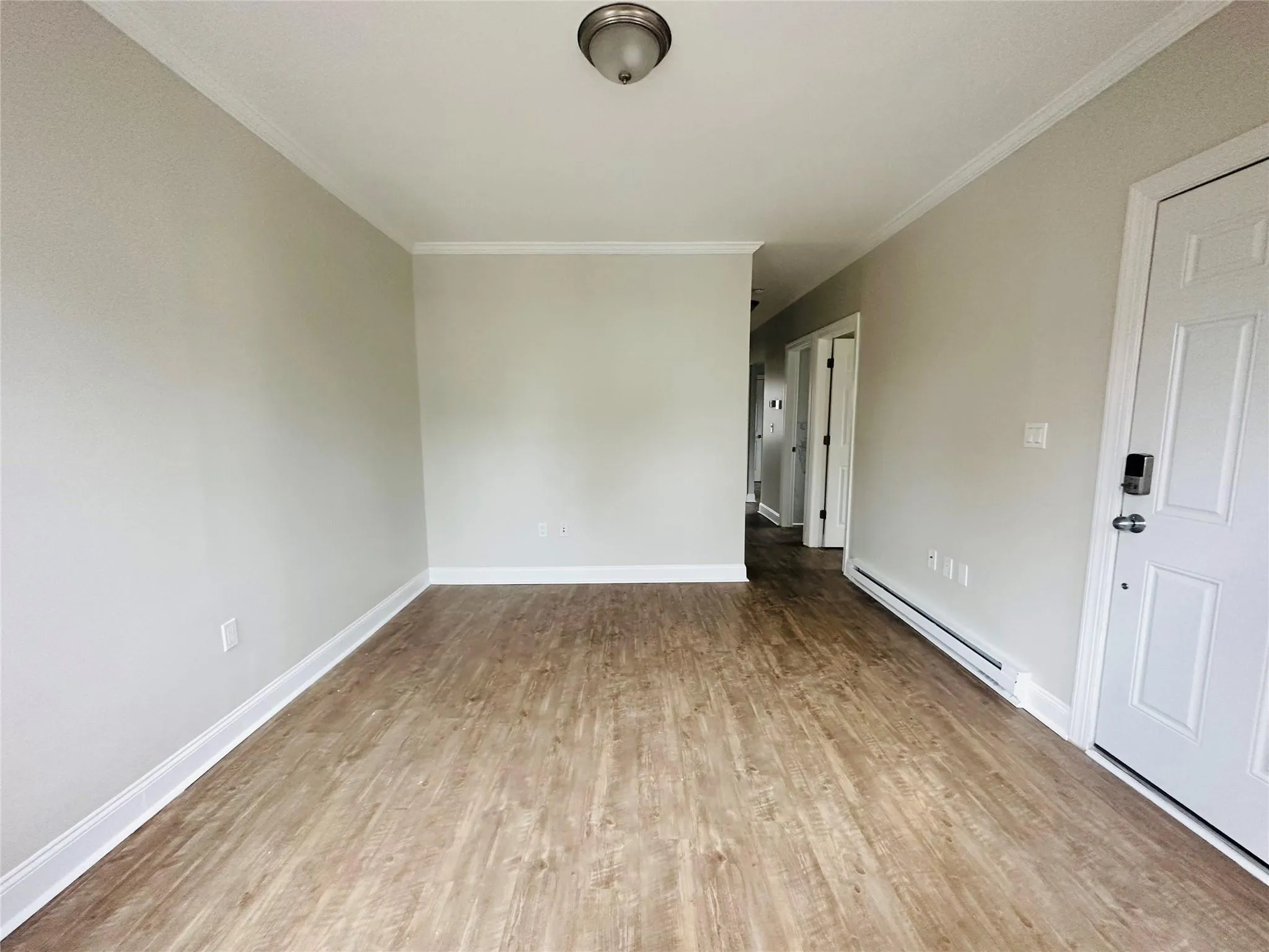 Empty room featuring crown molding, a baseboard radiator, and light hardwood / wood-style floors Empty room featuring crown molding, a baseboard radiator, and light hardwood / wood-style floors