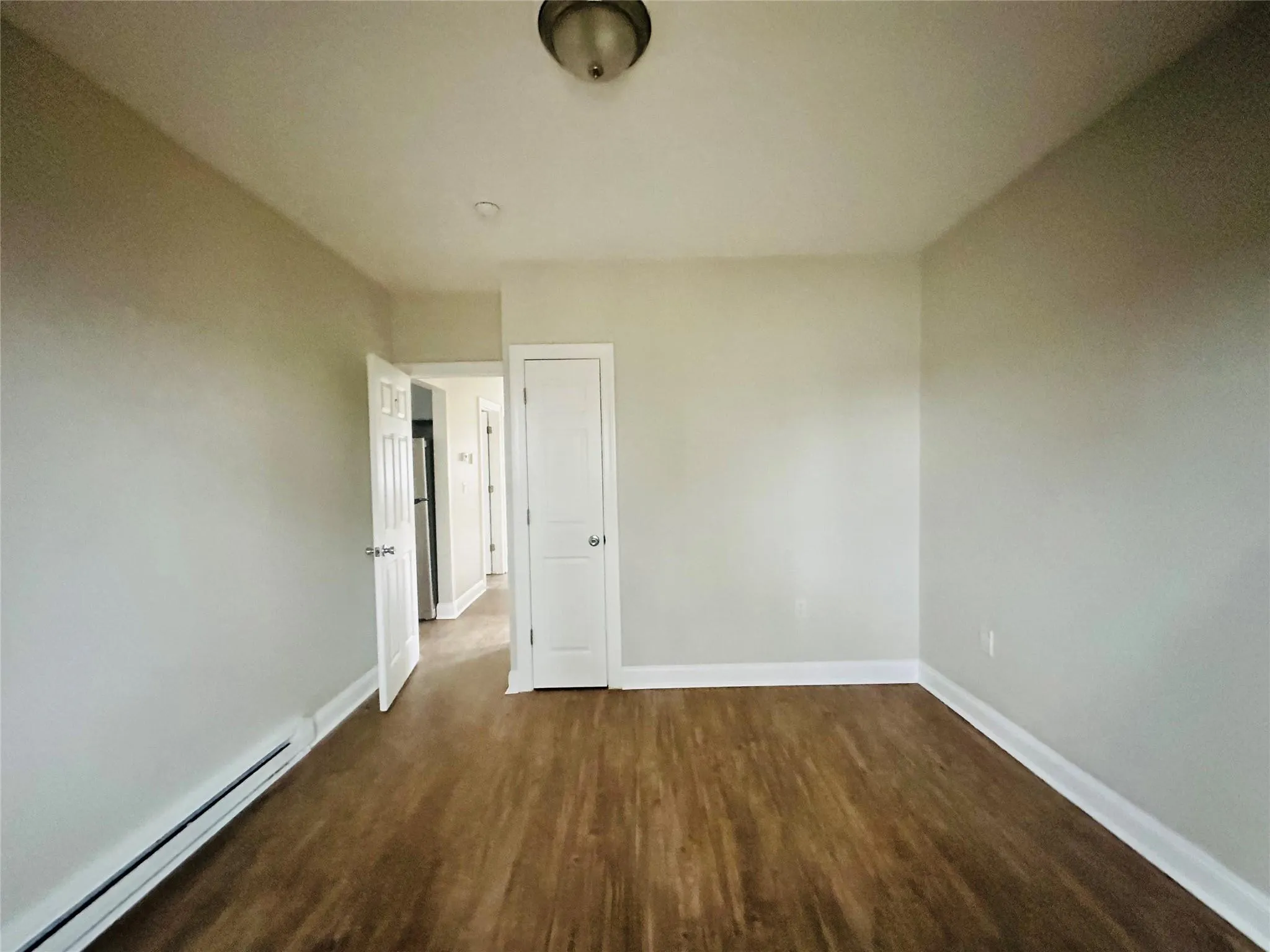 Empty room featuring a baseboard radiator and dark hardwood / wood-style floors Empty room featuring a baseboard radiator and dark hardwood / wood-style floors