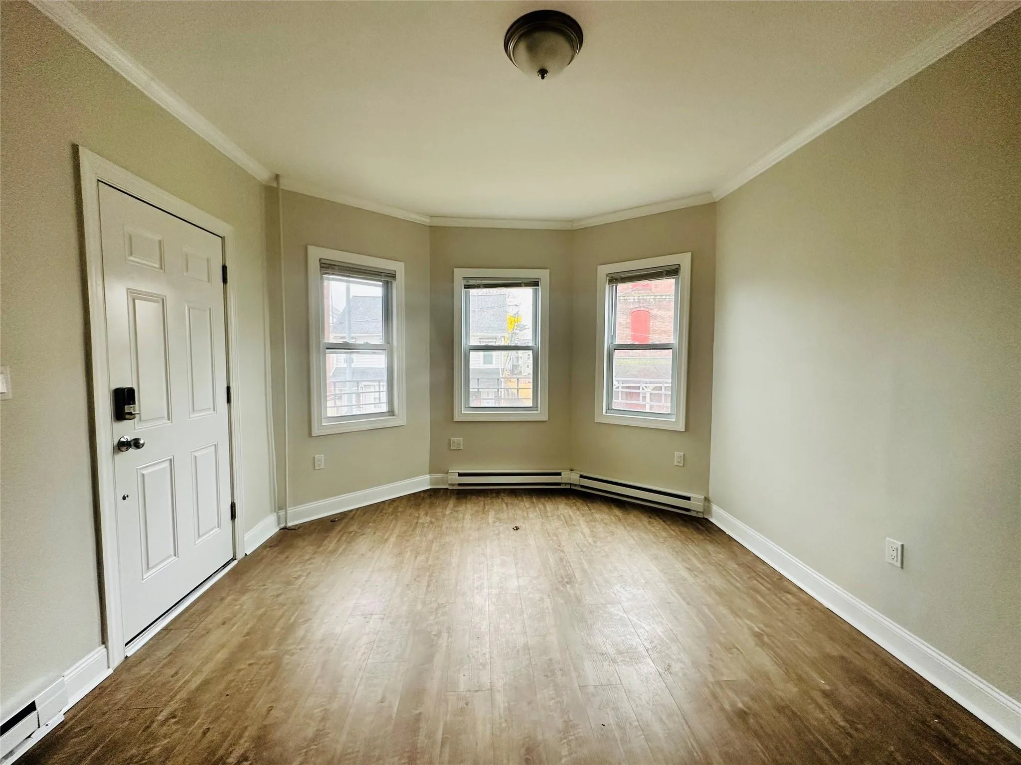 Unfurnished room with ornamental molding, wood-type flooring, and a baseboard heating unit Unfurnished room with ornamental molding, wood-type flooring, and a baseboard heating unit