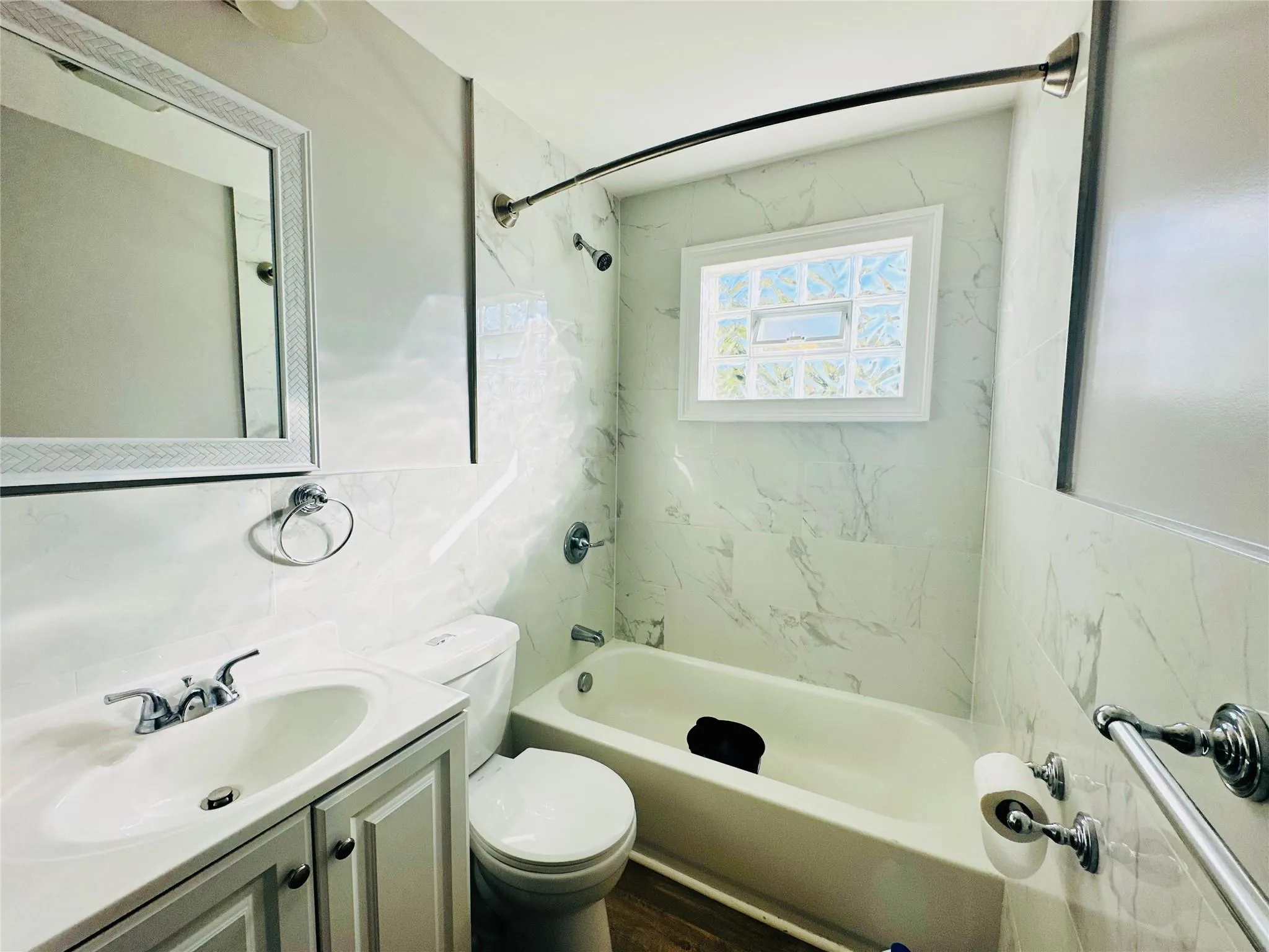 Full bathroom featuring tiled shower / bath combo, hardwood / wood-style floors, toilet, vanity, and tile walls Full bathroom featuring tiled shower / bath combo, hardwood / wood-style floors, toilet, vanity, and tile walls