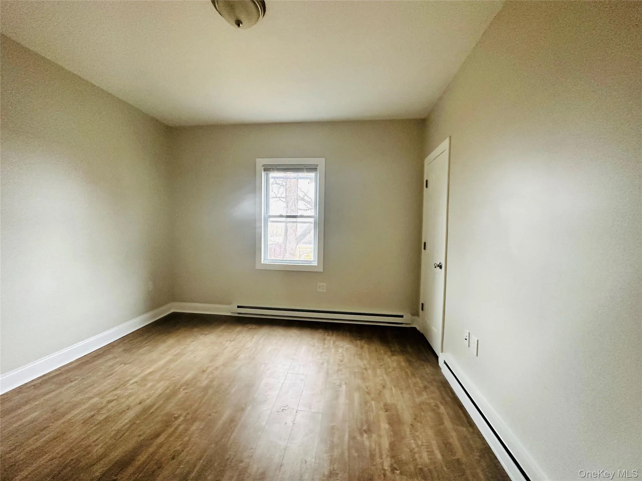 Unfurnished room featuring hardwood / wood-style floors and a baseboard heating unit Unfurnished room featuring hardwood / wood-style floors and a baseboard heating unit