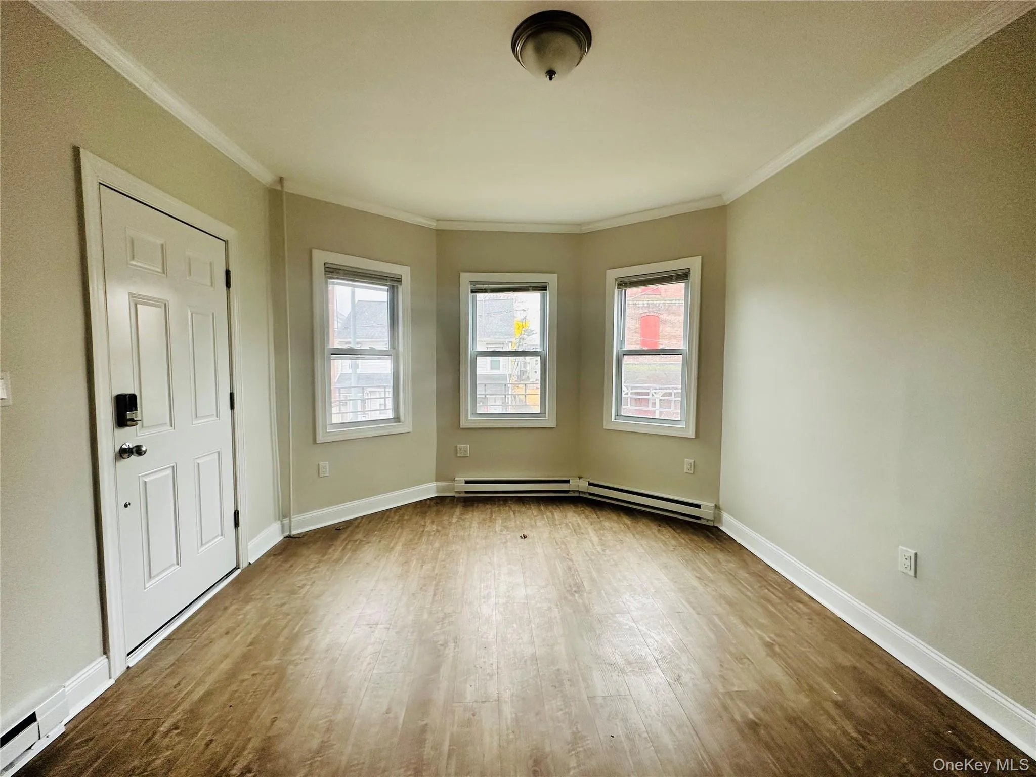 Unfurnished room with ornamental molding, wood-type flooring, and a baseboard heating unit Unfurnished room with ornamental molding, wood-type flooring, and a baseboard heating unit