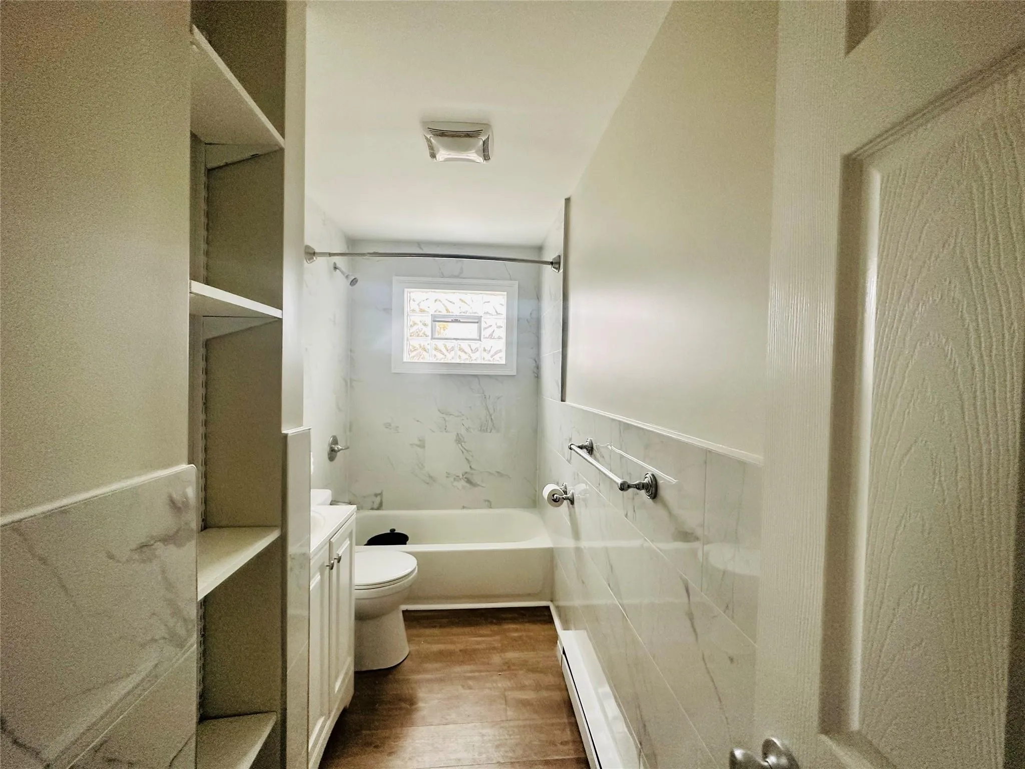 Full bathroom with vanity, tiled shower / bath combo, a baseboard radiator, hardwood / wood-style floors, and toilet Full bathroom with vanity, tiled shower / bath combo, a baseboard radiator, hardwood / wood-style floors, and toilet
