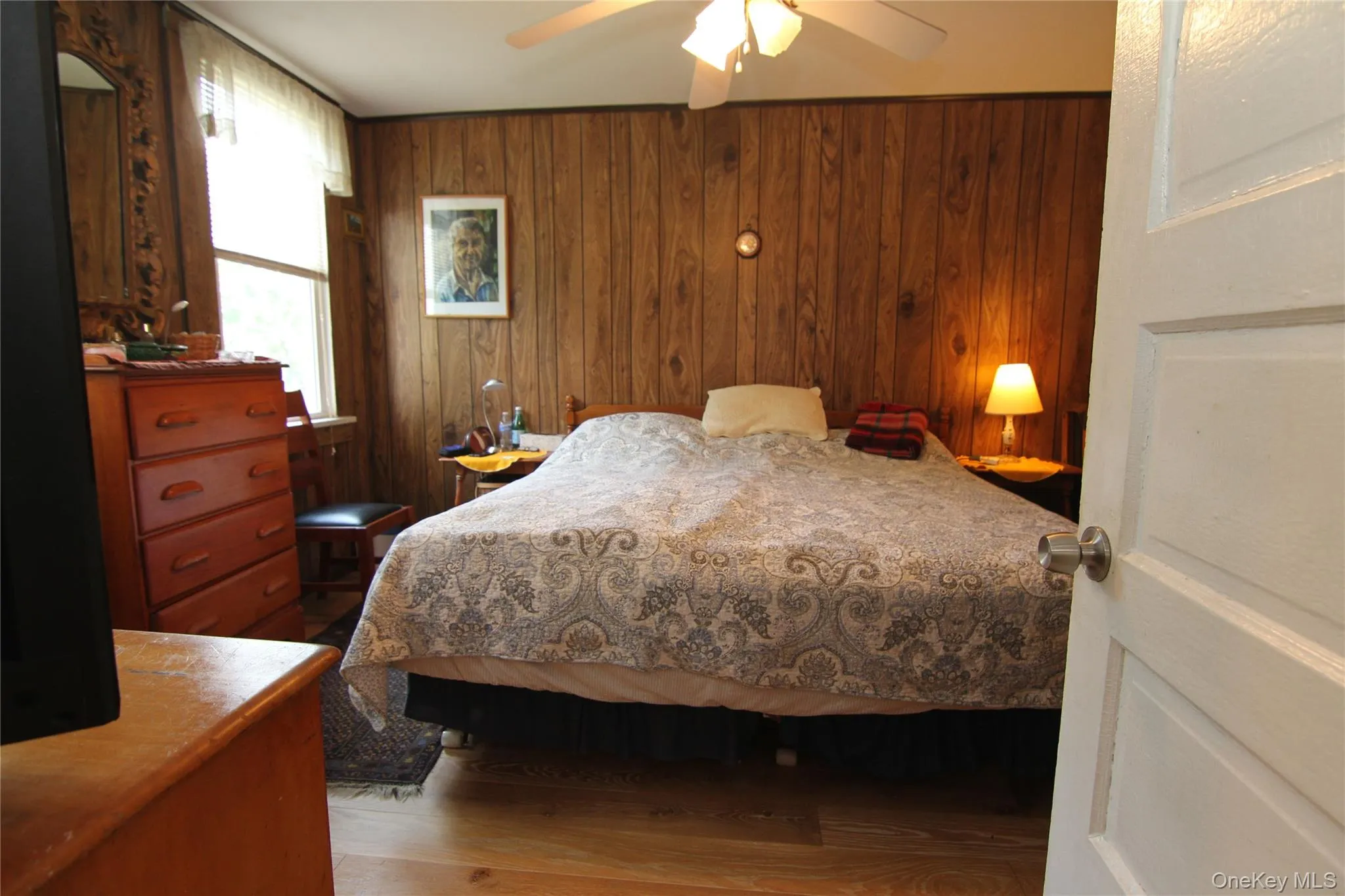 Bedroom with wood finished floors, wood walls, and a ceiling fan Bedroom with wood finished floors, wood walls, and a ceiling fan