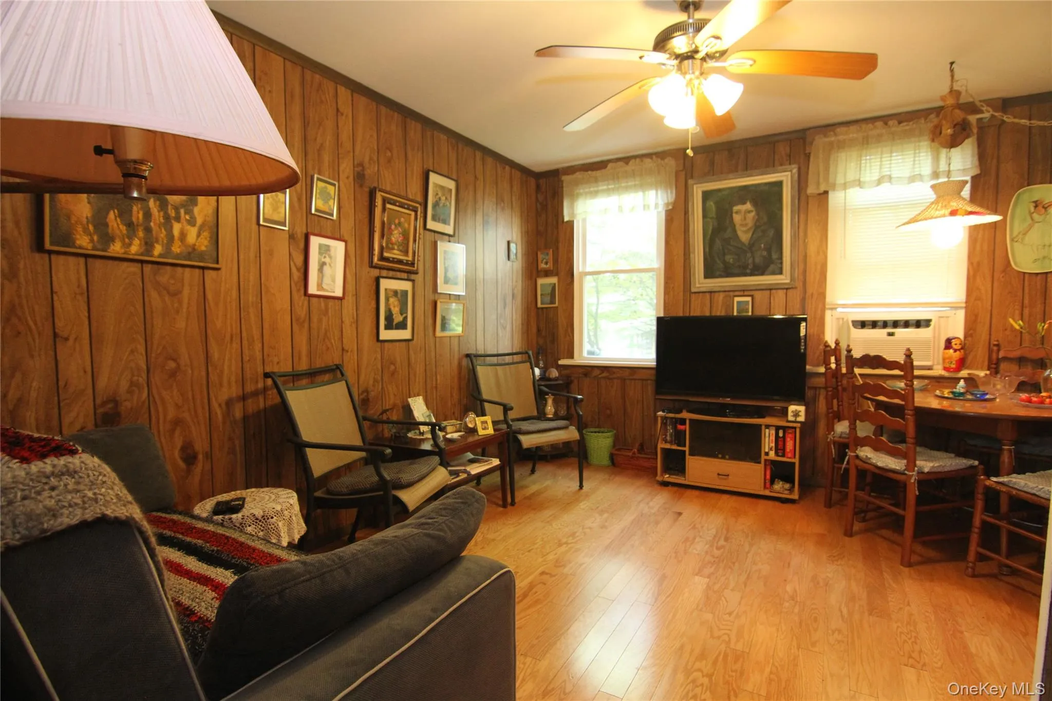 Living area featuring ceiling fan, wood walls, wood finished floors, cooling unit, and crown molding Living area featuring ceiling fan, wood walls, wood finished floors, cooling unit, and crown molding