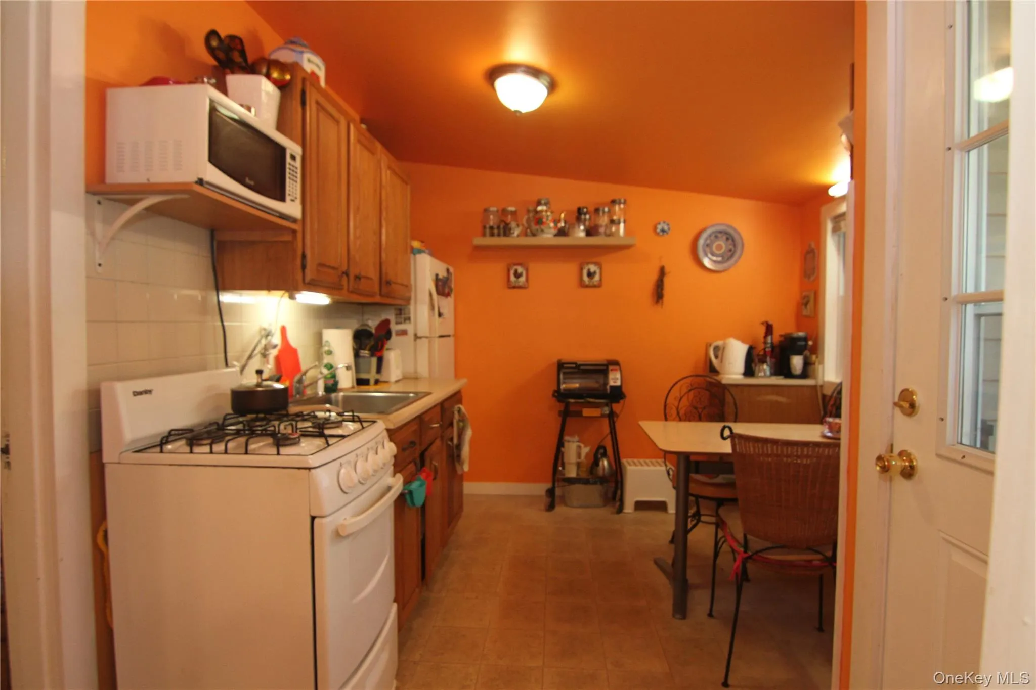 Kitchen with white appliances, light countertops, brown cabinets, and light tile patterned flooring Kitchen with white appliances, light countertops, brown cabinets, and light tile patterned flooring