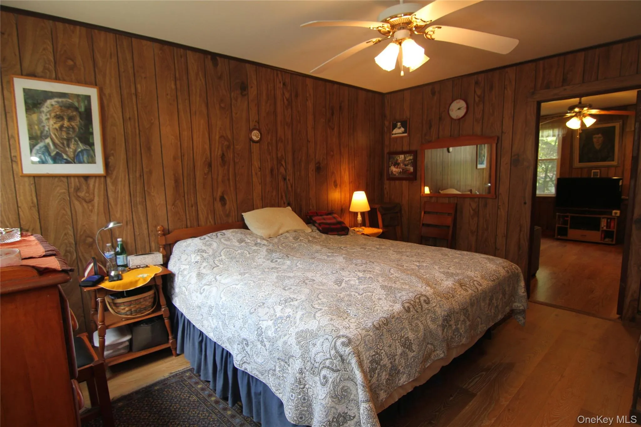 Bedroom featuring wood finished floors, wood walls, and ceiling fan Bedroom featuring wood finished floors, wood walls, and ceiling fan