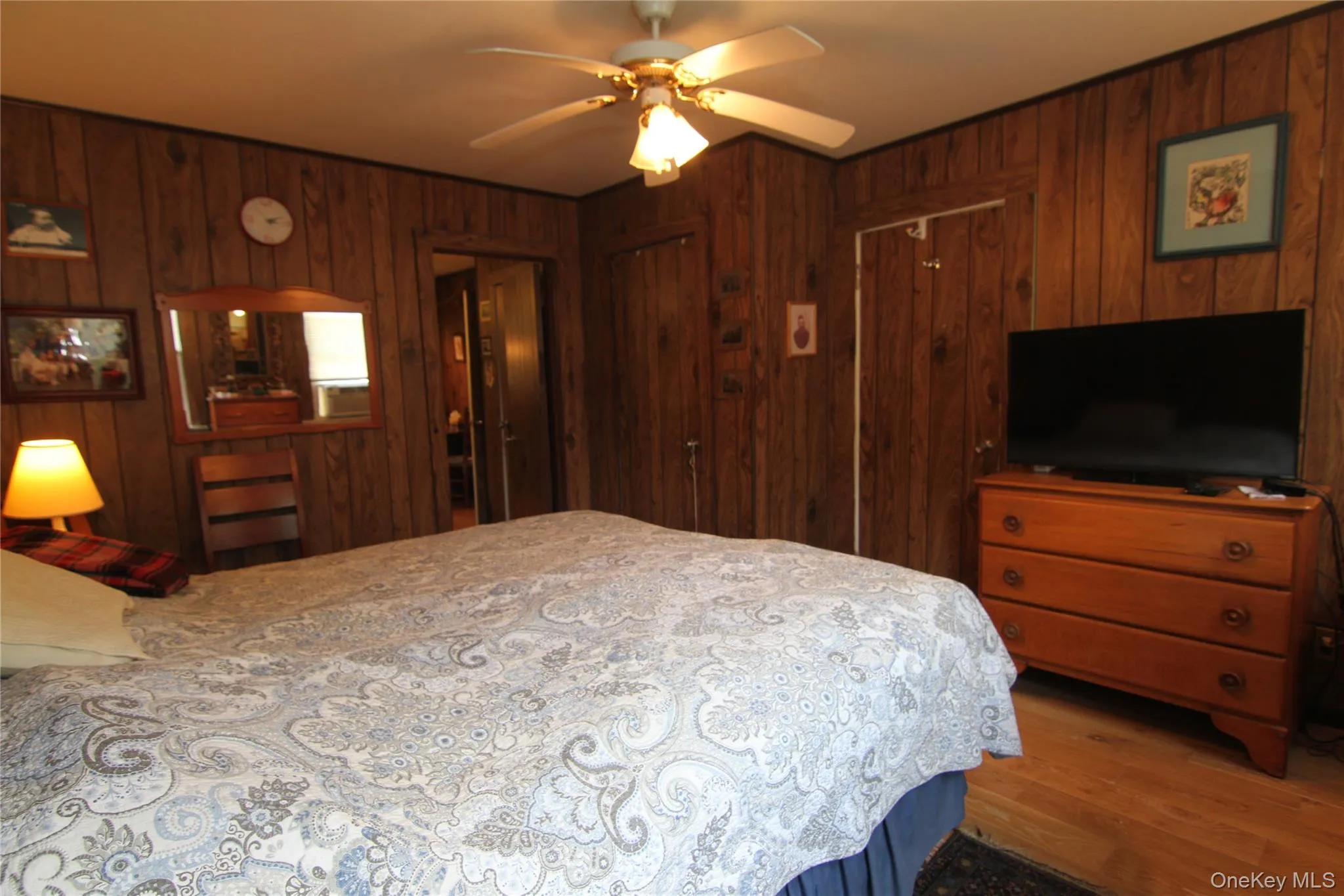 Bedroom featuring wood walls, wood finished floors, and a ceiling fan Bedroom featuring wood walls, wood finished floors, and a ceiling fan