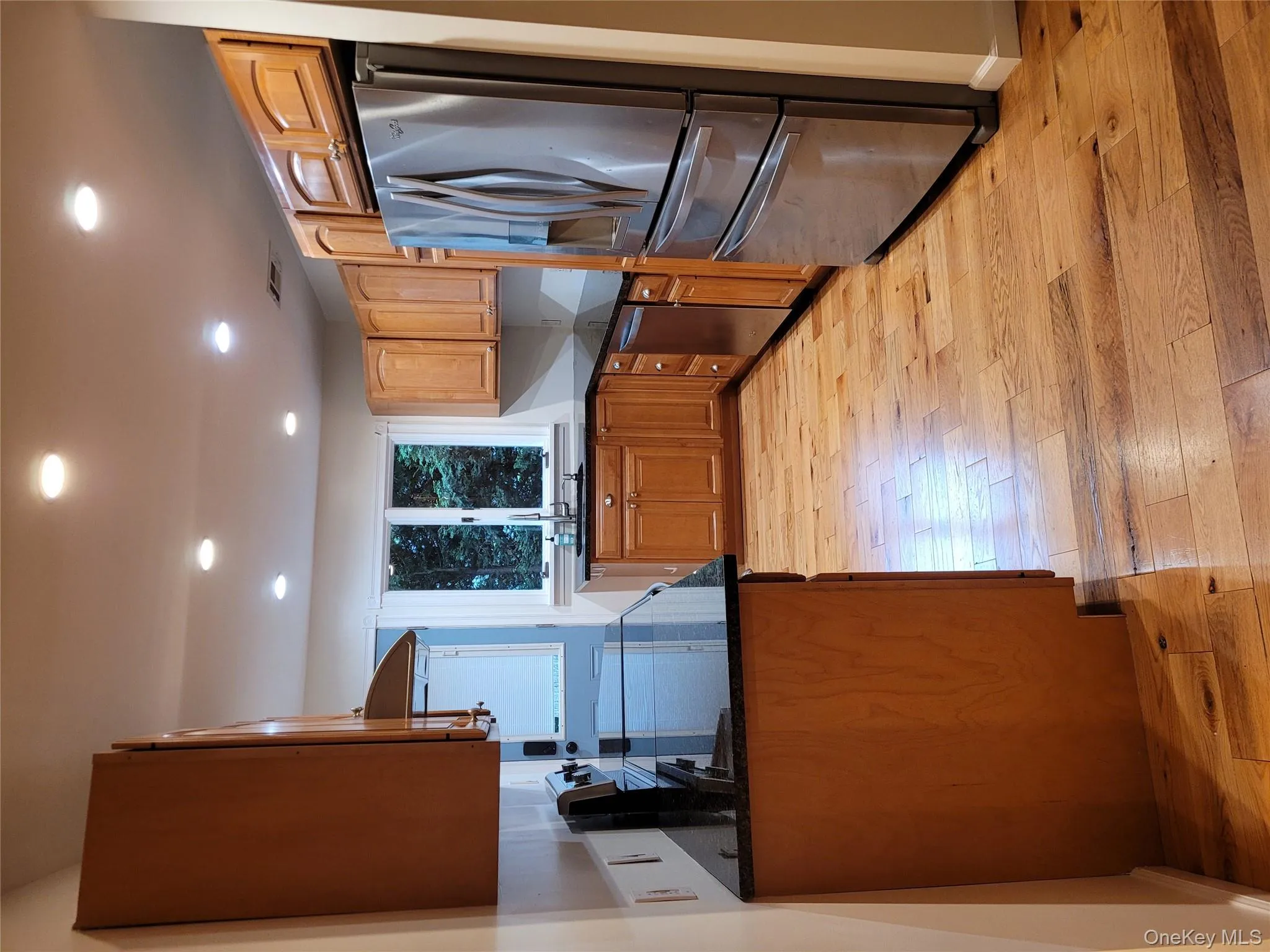 Kitchen featuring fridge, dishwashing machine, light wood finished floors, recessed lighting, and dark stone counters Kitchen featuring fridge, dishwashing machine, light wood finished floors, recessed lighting, and dark stone counters