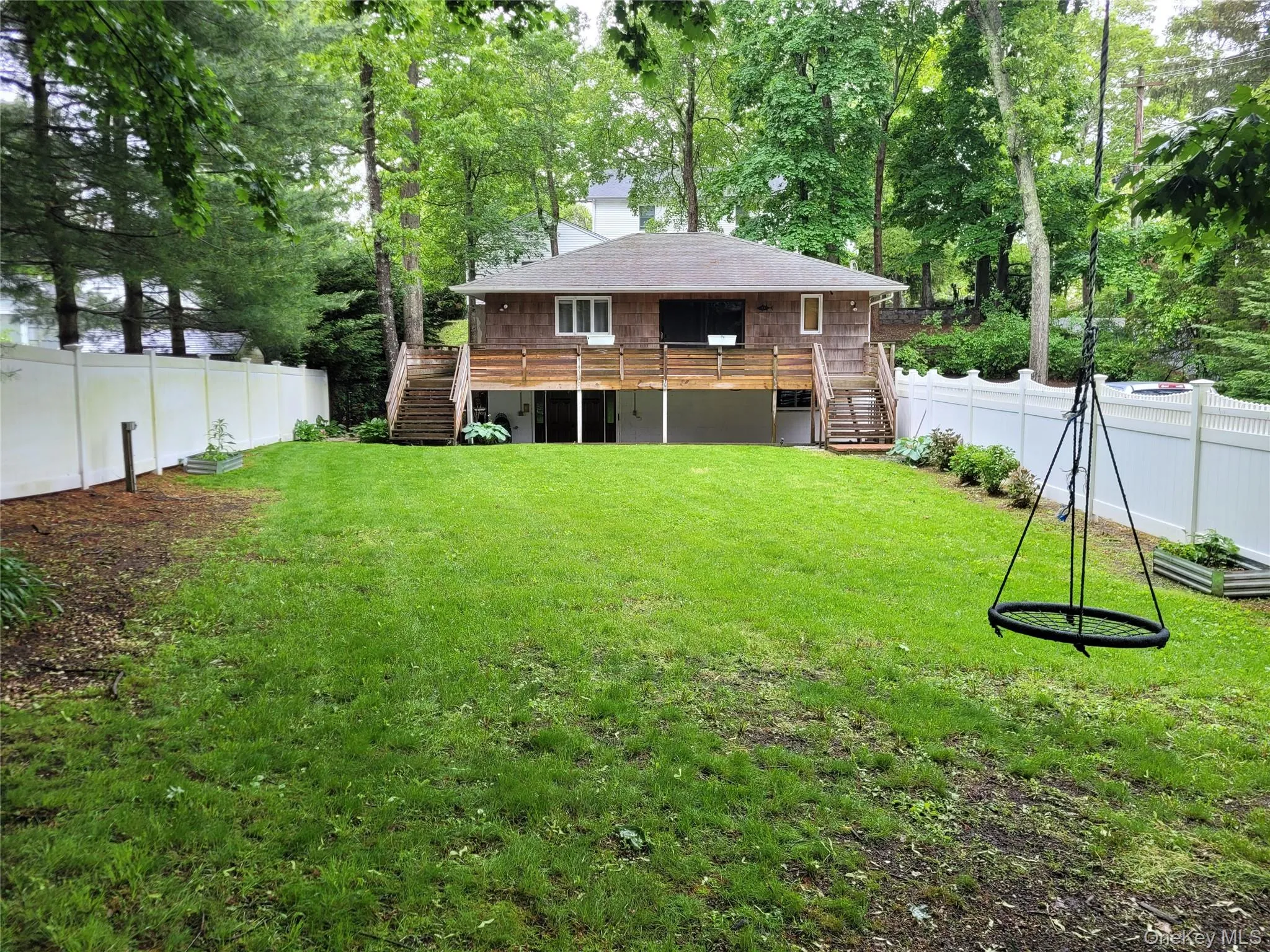 Rear view of house with stairway, a fenced backyard, a deck, and a chimney Rear view of house with stairway, a fenced backyard, a deck, and a chimney