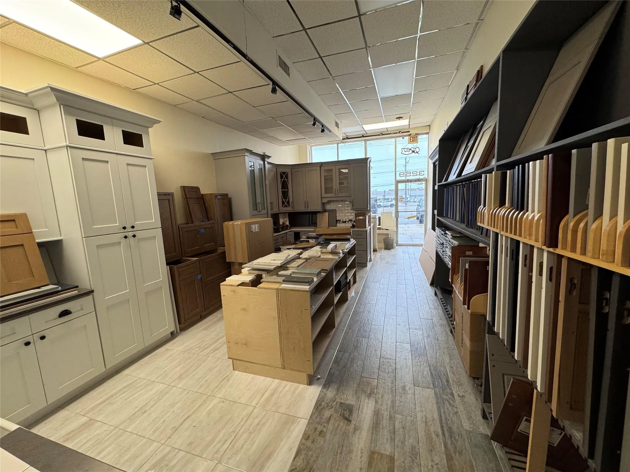 Kitchen featuring a paneled ceiling, a kitchen island, glass insert cabinets, floor to ceiling windows, and light wood-type flooring Kitchen featuring a paneled ceiling, a kitchen island, glass insert cabinets, floor to ceiling windows, and light wood-type flooring