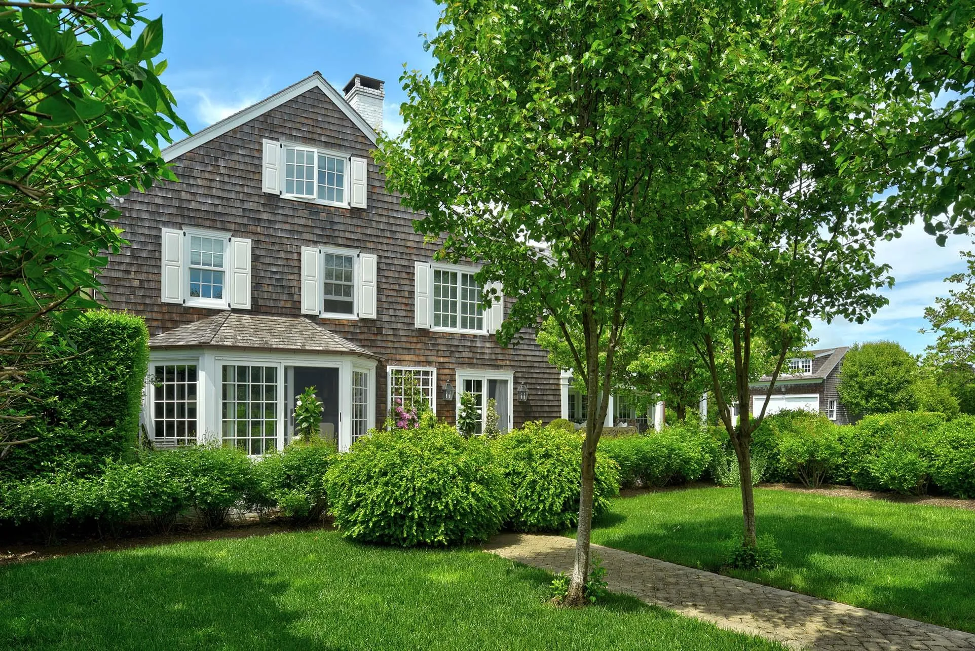 Shingle-style home with a chimney and a front yard Shingle-style home with a chimney and a front yard