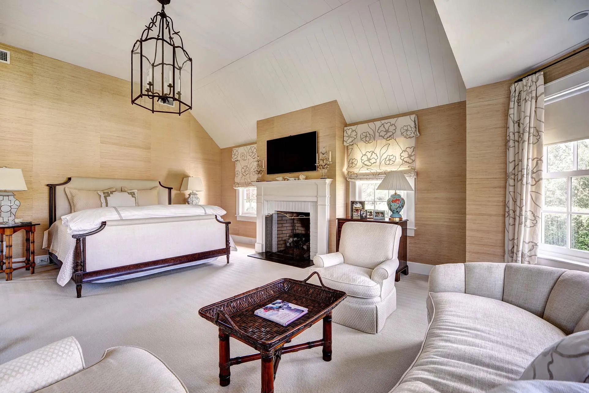Carpeted bedroom featuring wallpapered walls, a brick fireplace, and a chandelier Carpeted bedroom featuring wallpapered walls, a brick fireplace, and a chandelier