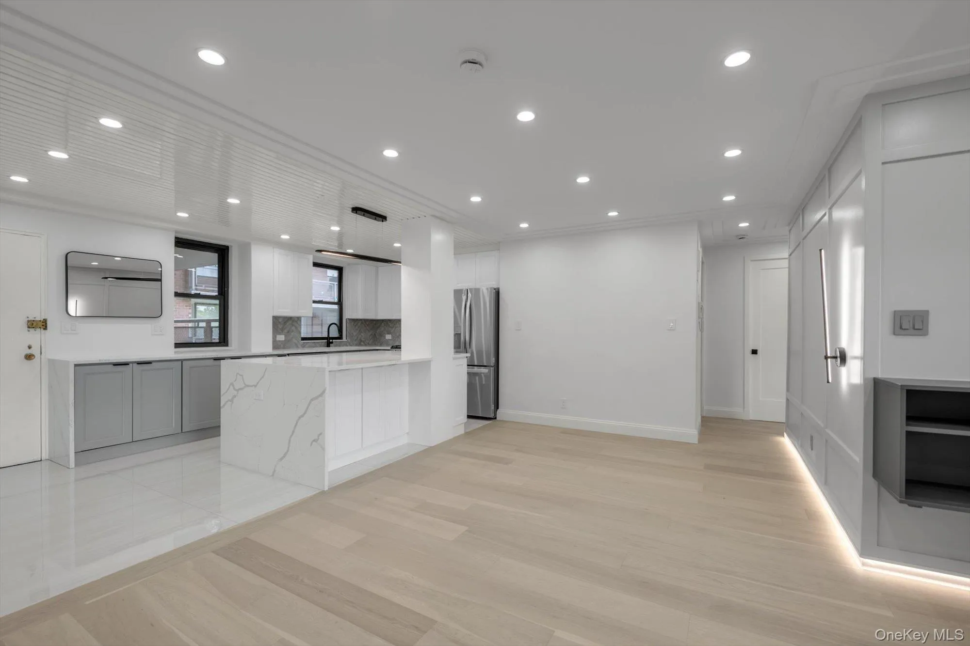 Kitchen with stainless steel fridge with ice dispenser, light wood-type flooring, backsplash, white cabinets, and recessed lighting Kitchen with stainless steel fridge with ice dispenser, light wood-type flooring, backsplash, white cabinets, and recessed lighting