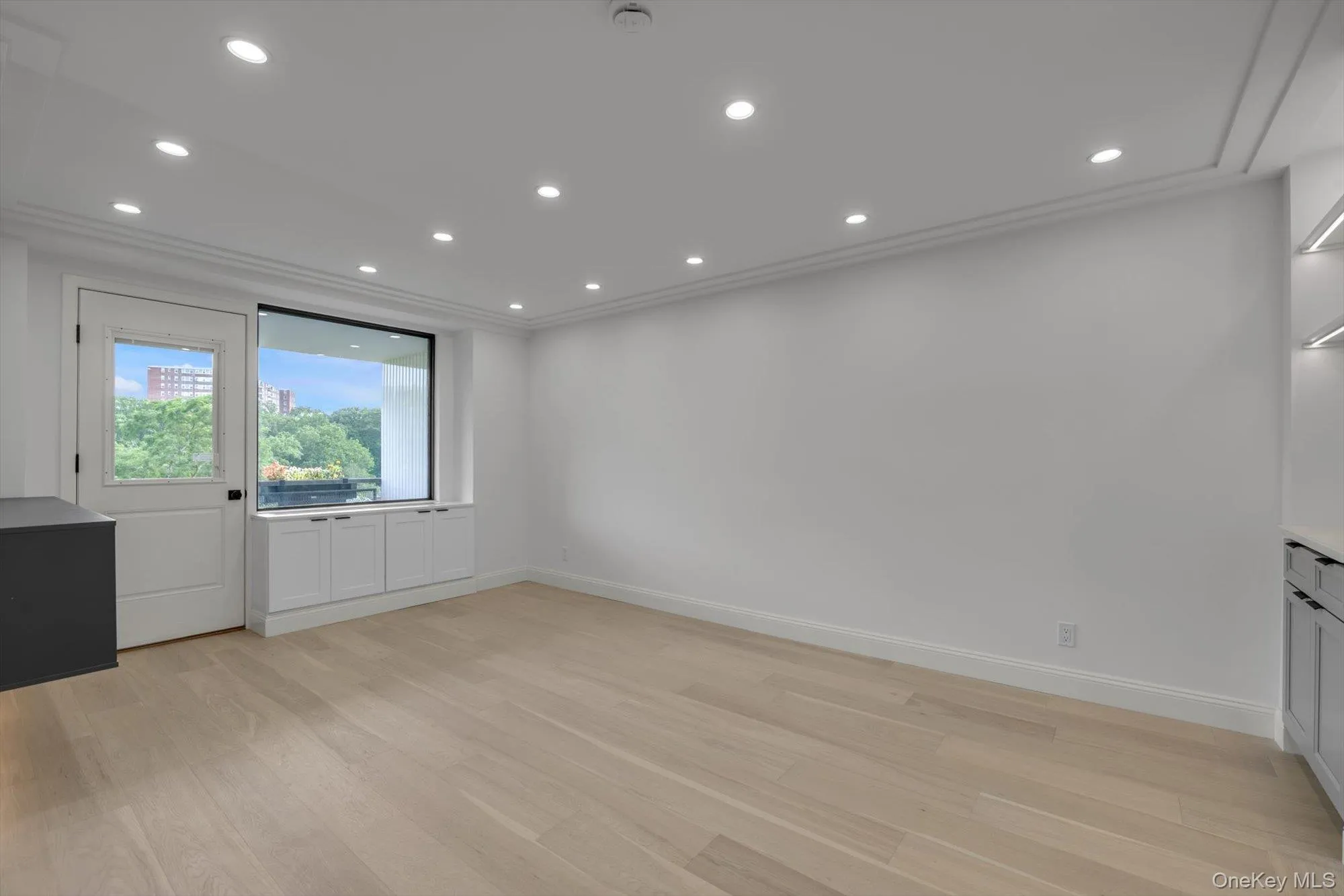Empty room featuring light wood-style flooring, recessed lighting, crown molding, and a smoke detector Empty room featuring light wood-style flooring, recessed lighting, crown molding, and a smoke detector