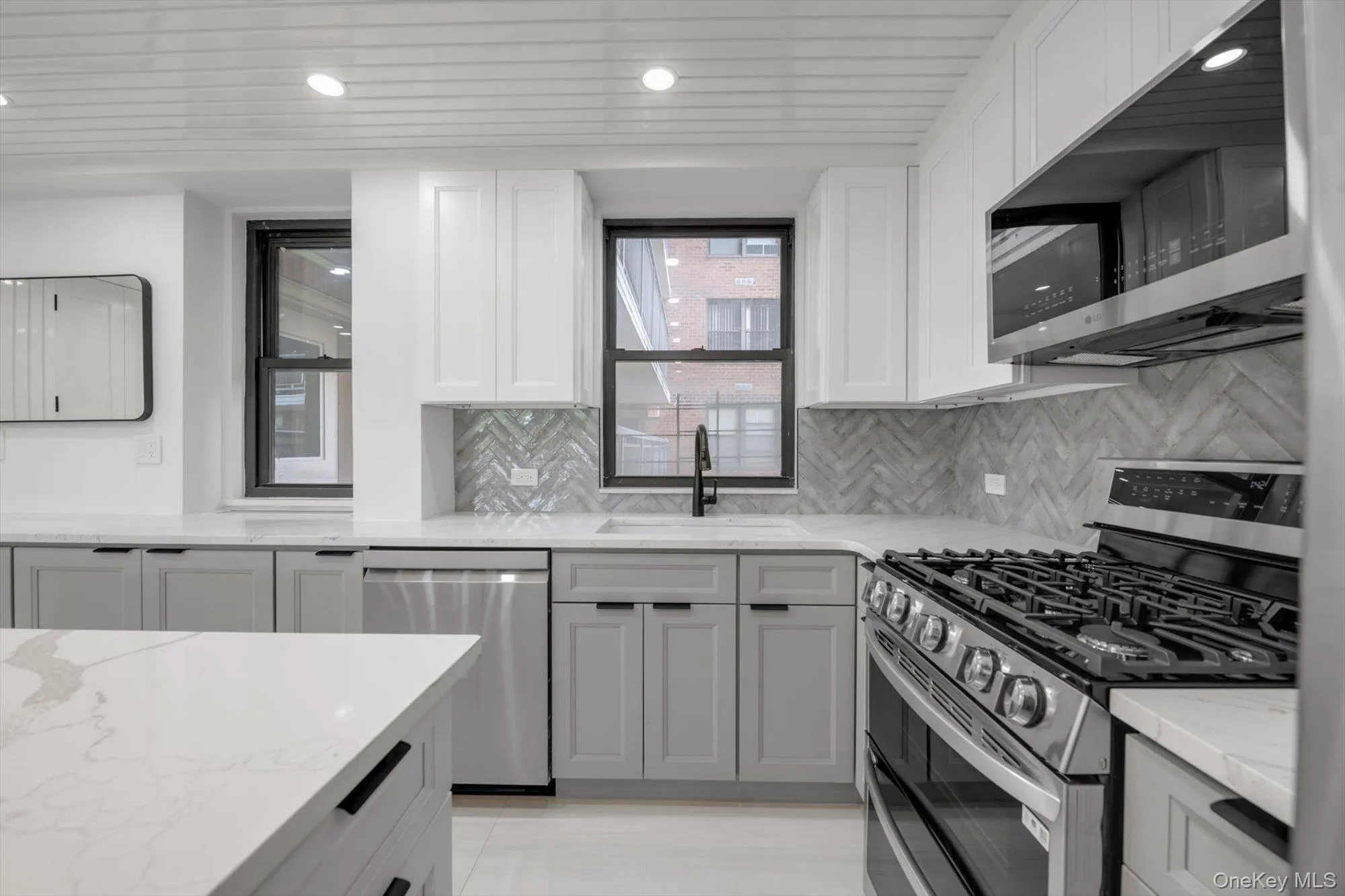 Kitchen featuring appliances with stainless steel finishes, light stone countertops, tasteful backsplash, white cabinets, and recessed lighting Kitchen featuring appliances with stainless steel finishes, light stone countertops, tasteful backsplash, white cabinets, and recessed lighting